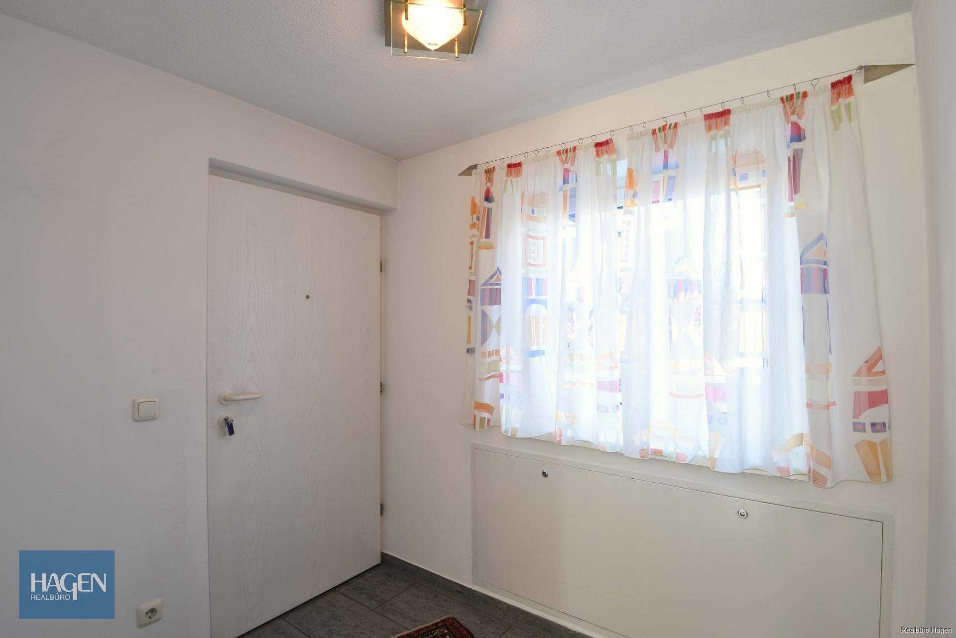 Eingangsbereich mit Fenster und farbenfrohen Vorhängen, bietet einen freundlichen Empfang.