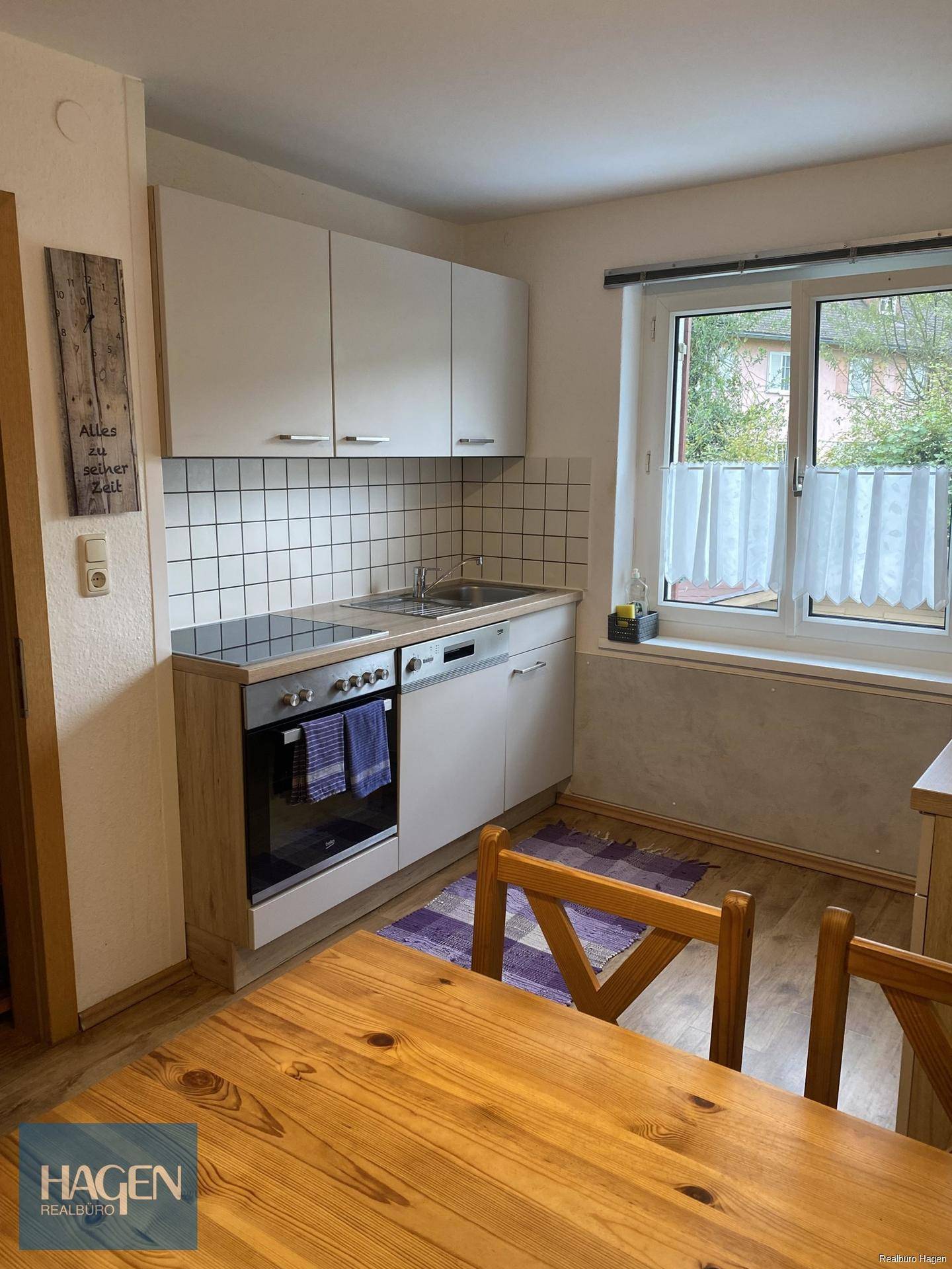 Funktionale Küche mit Essbereich, Fenster und weißen Oberschränken sowie modernen Geräten.