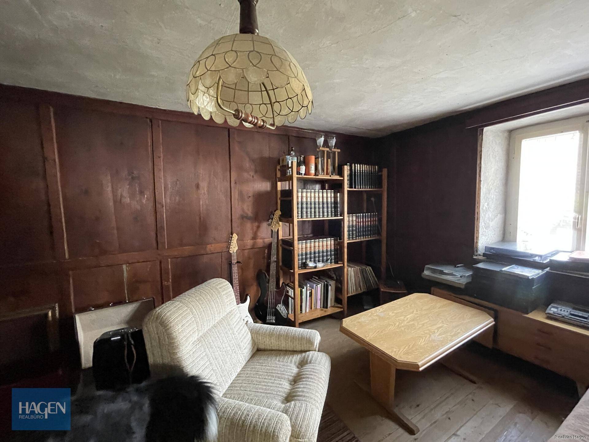 Gemütliches Wohnzimmer mit dunkler Holzvertäfelung, bequemen Möbeln und Bücherregalen.