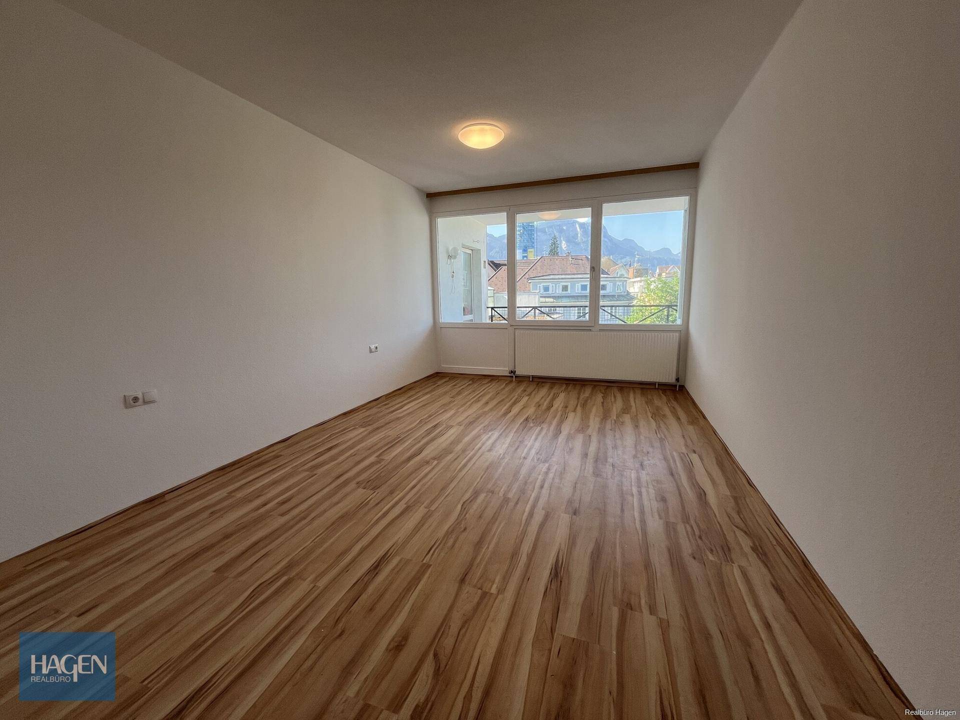 Helles Wohnzimmer mit Laminatboden und weitem Blick auf die umliegende Berglandschaft.