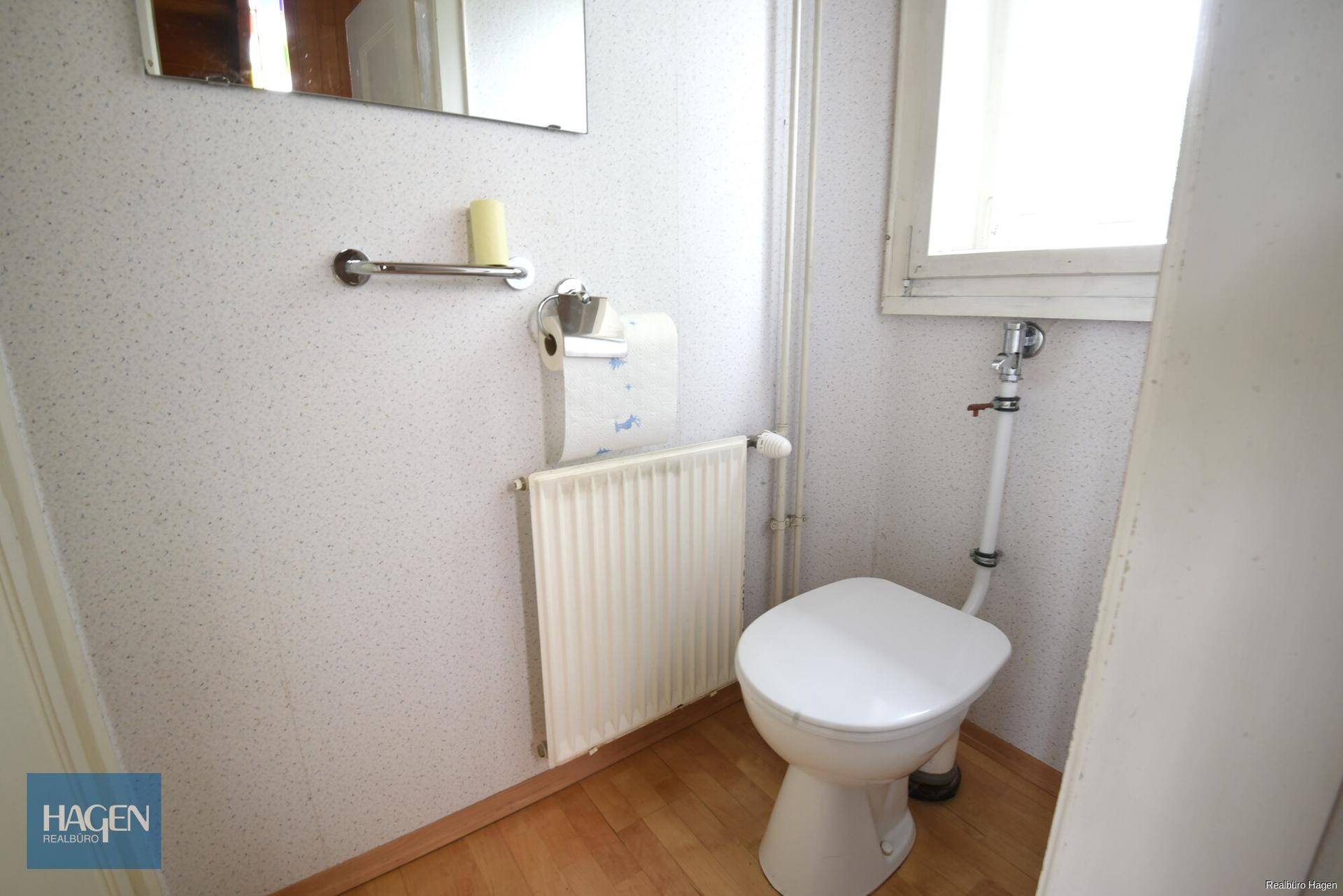 Separate Toilette mit Fenster, Heizkörper und hellem Holzboden.