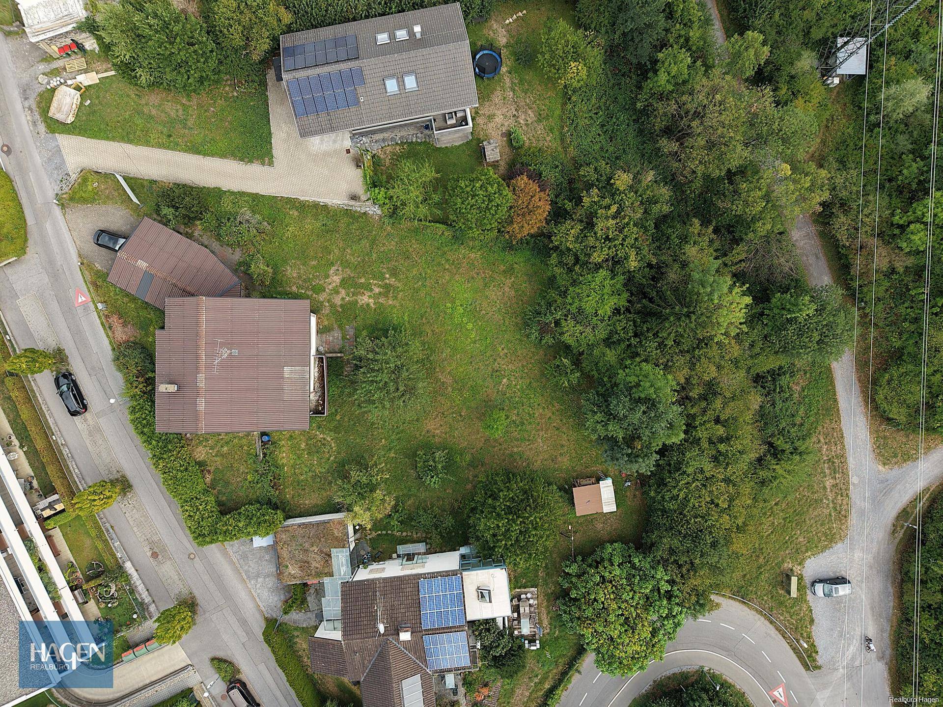 Vogelperspektive des Grundstücks mit Haus, Garten und angrenzenden Waldgebieten.
