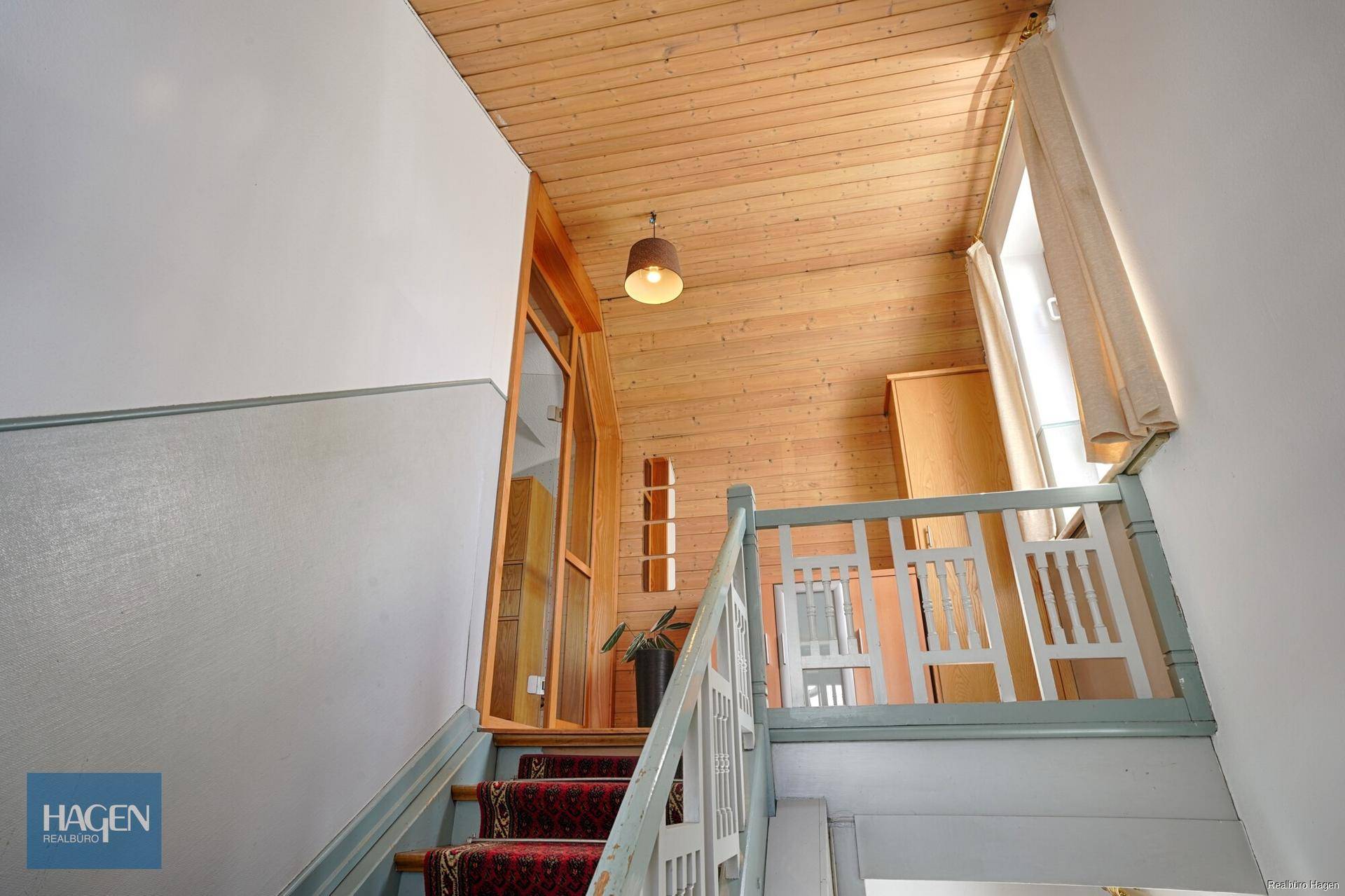 Treppenhaus mit Holzverkleidung an der Decke und Wänden, führt zu oberen Etagen.