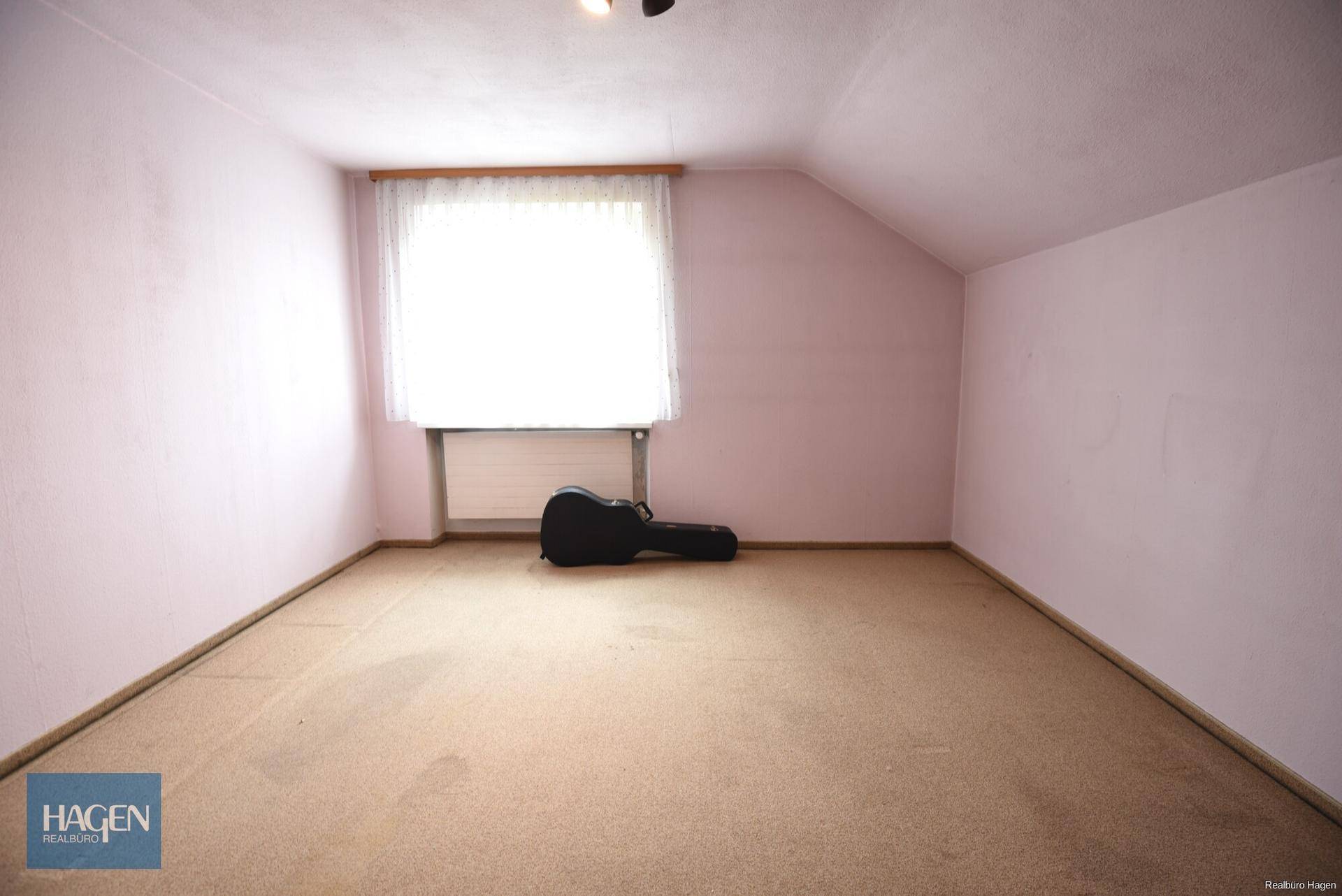 Dachgeschosszimmer mit rosa Wänden, Teppichboden und Fenster.