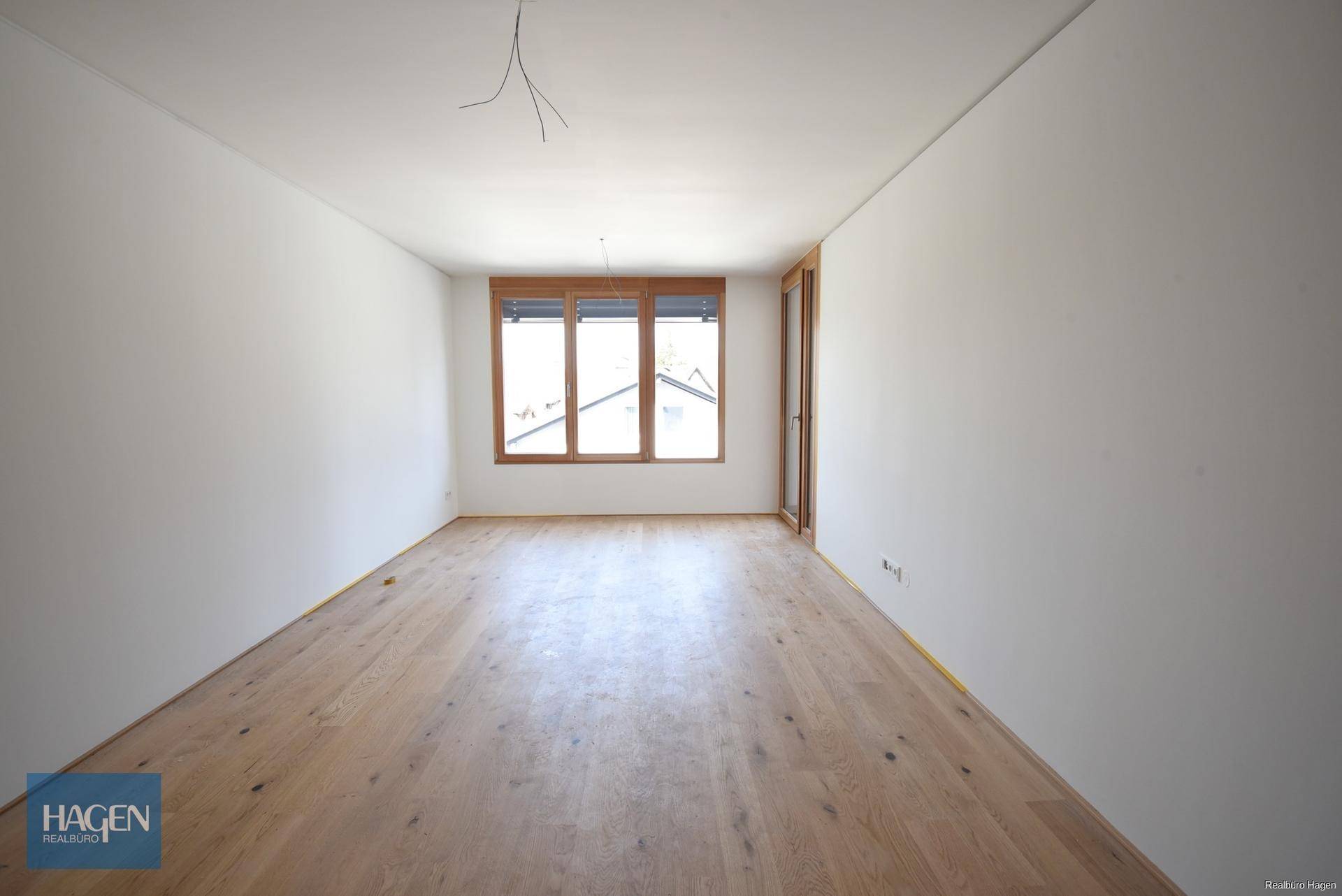 Leeres Zimmer mit Holzboden und großen Holzfenstern, bereit für die individuelle Gestaltung.