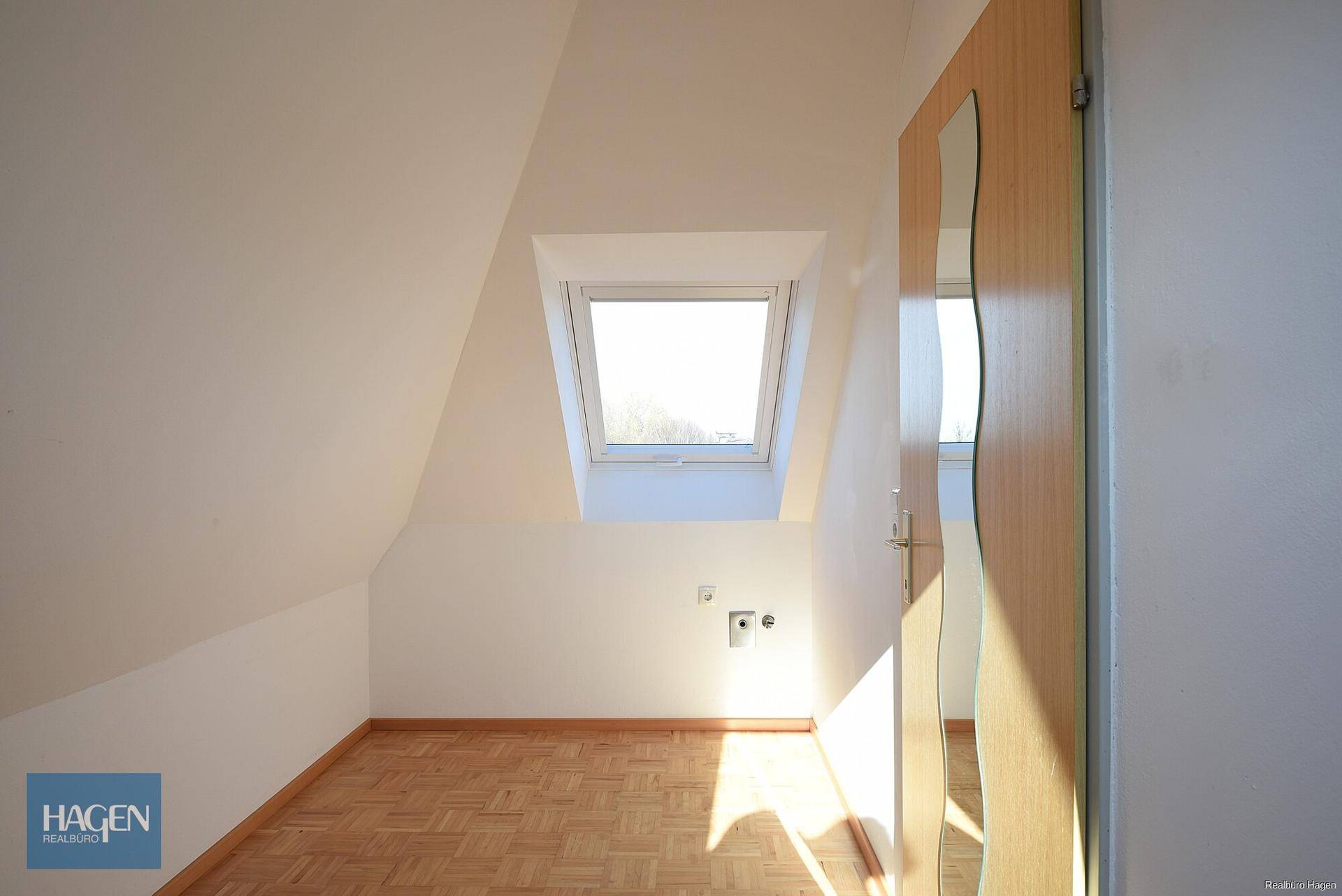 Gemütliches Schlafzimmer im Dachgeschoss mit Parkettboden, Dachfenster und Spiegeltür.