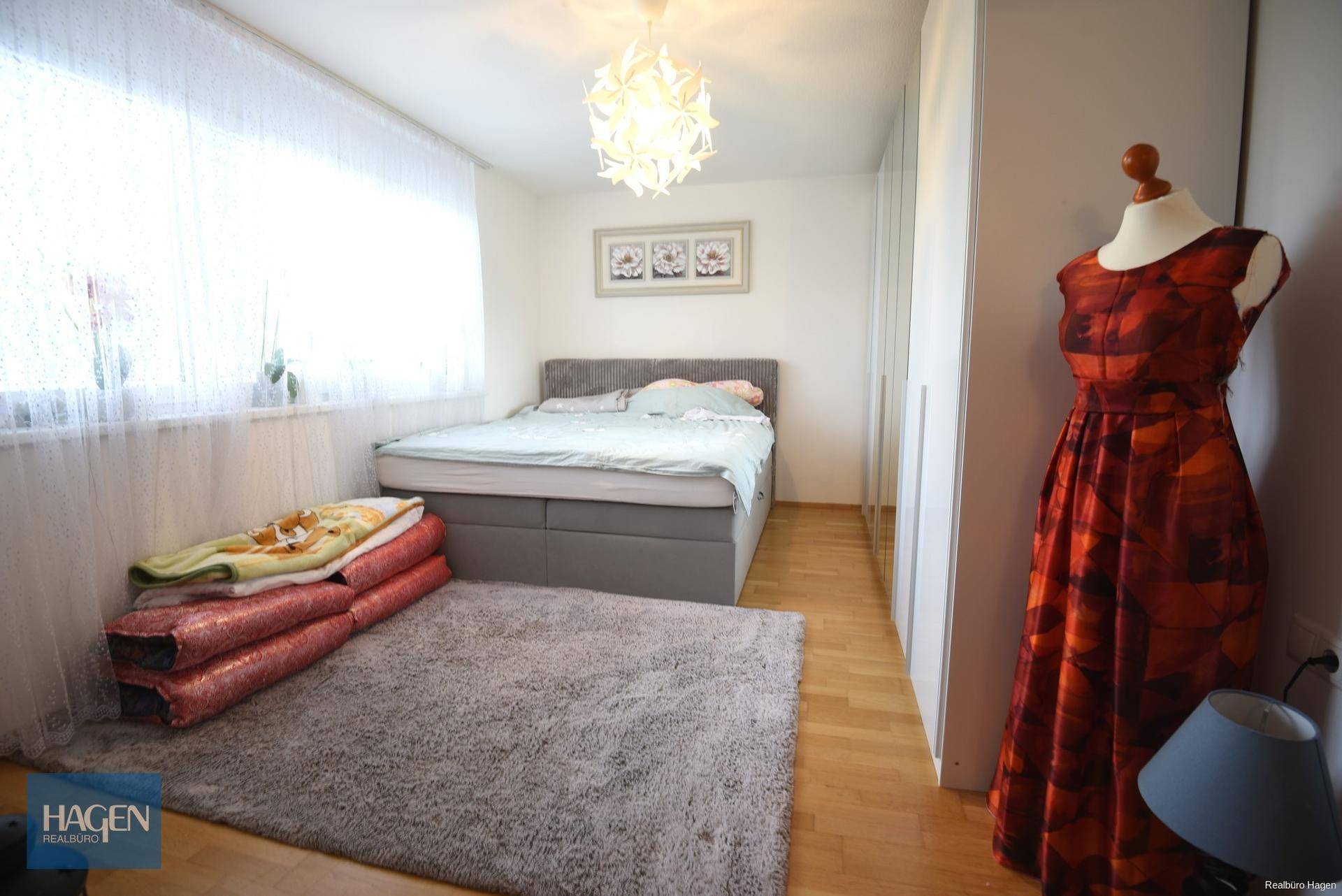 Helles Schlafzimmer mit Doppelbett, weichem Teppich und großem Fenster für viel Tageslicht.
