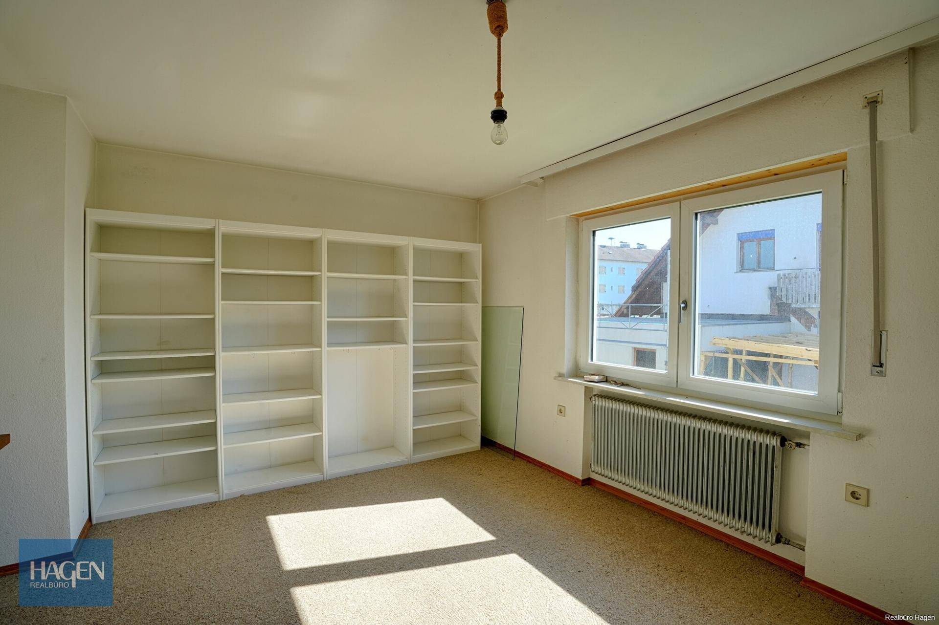 Geräumiges Zimmer mit Teppichboden, Einbauregalen und viel Tageslicht.
