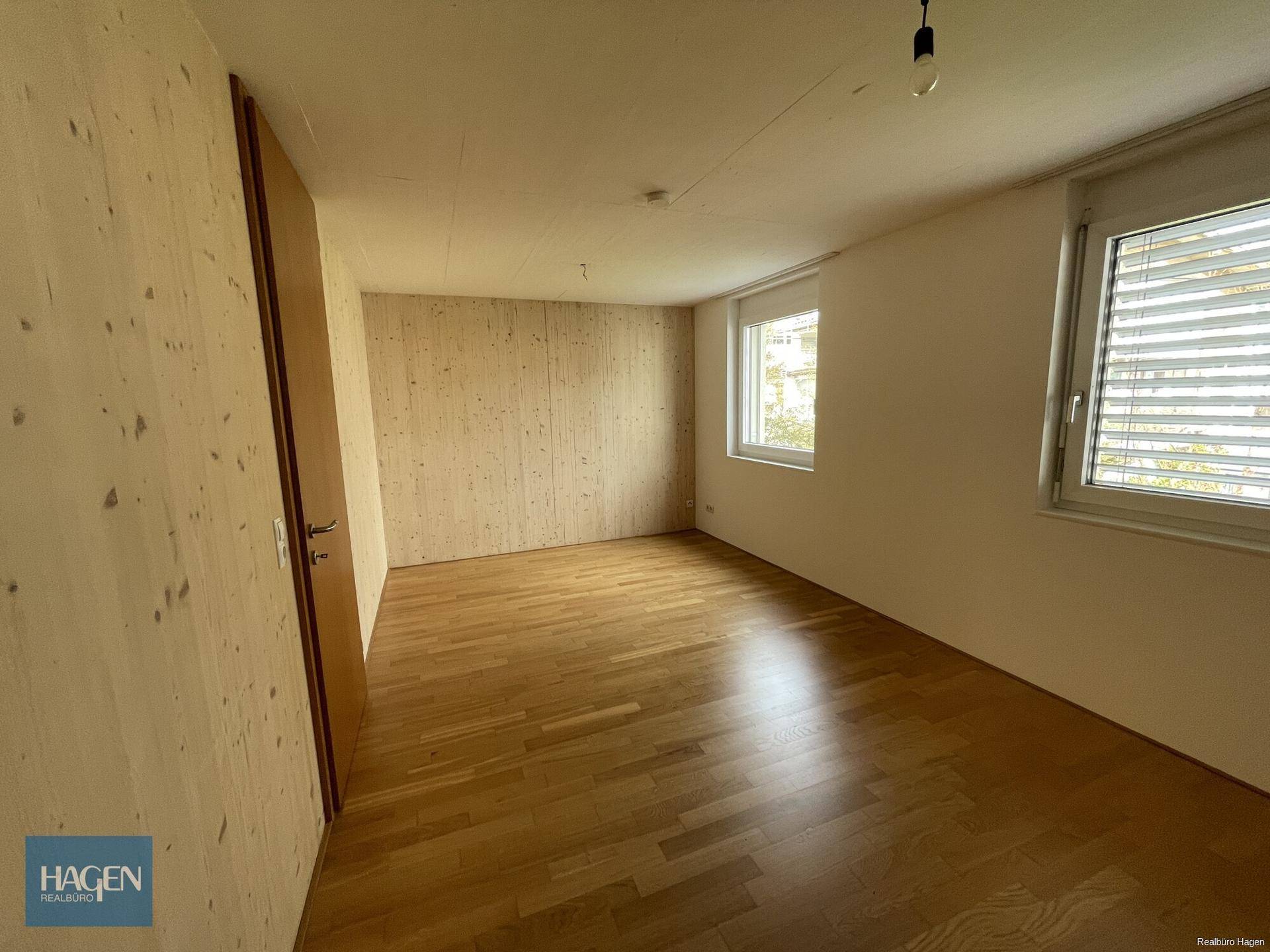 Geräumiges Schlafzimmer mit Holzboden und zwei Fenstern für optimale Belichtung.