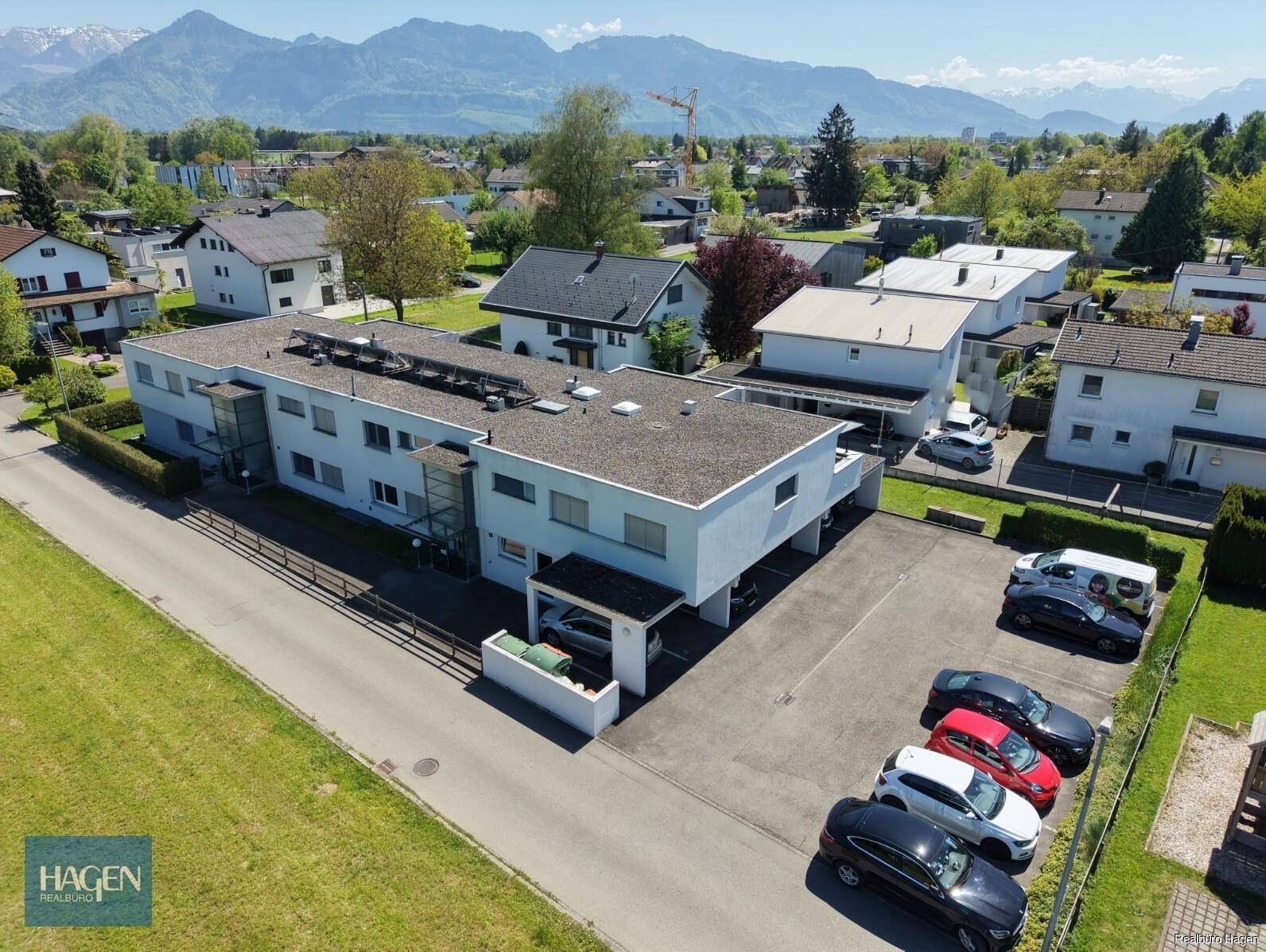 Panoramablick aus der Luft auf die Wohnanlage und die umliegende Wohngegend mit Bergen.