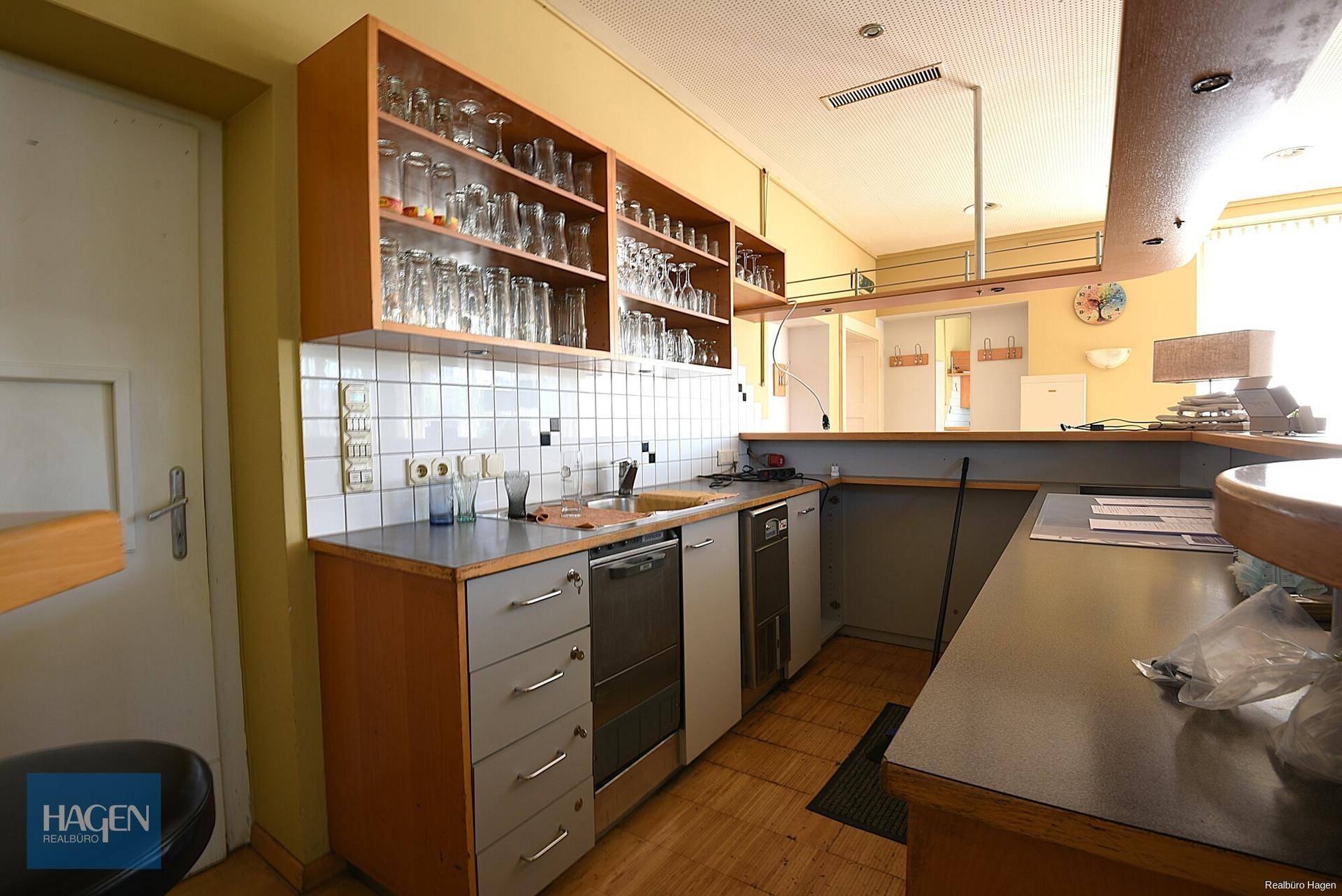 Küchenzeile mit Spülbecken, Geschirrspüler und vielen Gläsern, integriert in einen Thekenbereich.