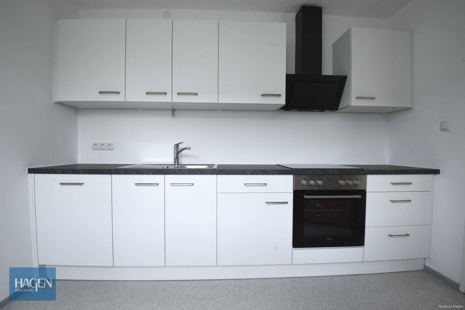 Neue, weiße Einbauküche mit dunkler Arbeitsplatte und modernen Elektrogeräten, bereit zur Nutzung.