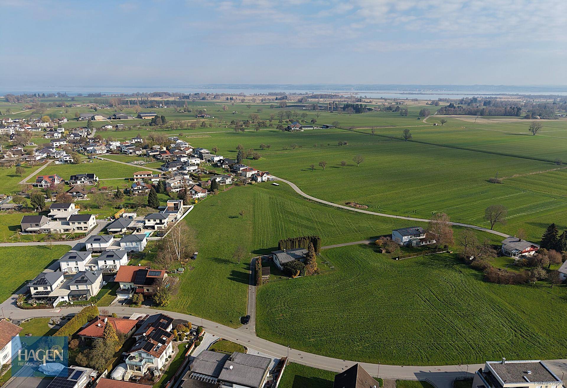 Weitläufige Luftaufnahme der Liegenschaft mit umliegenden Feldern und einem See in der Ferne.
