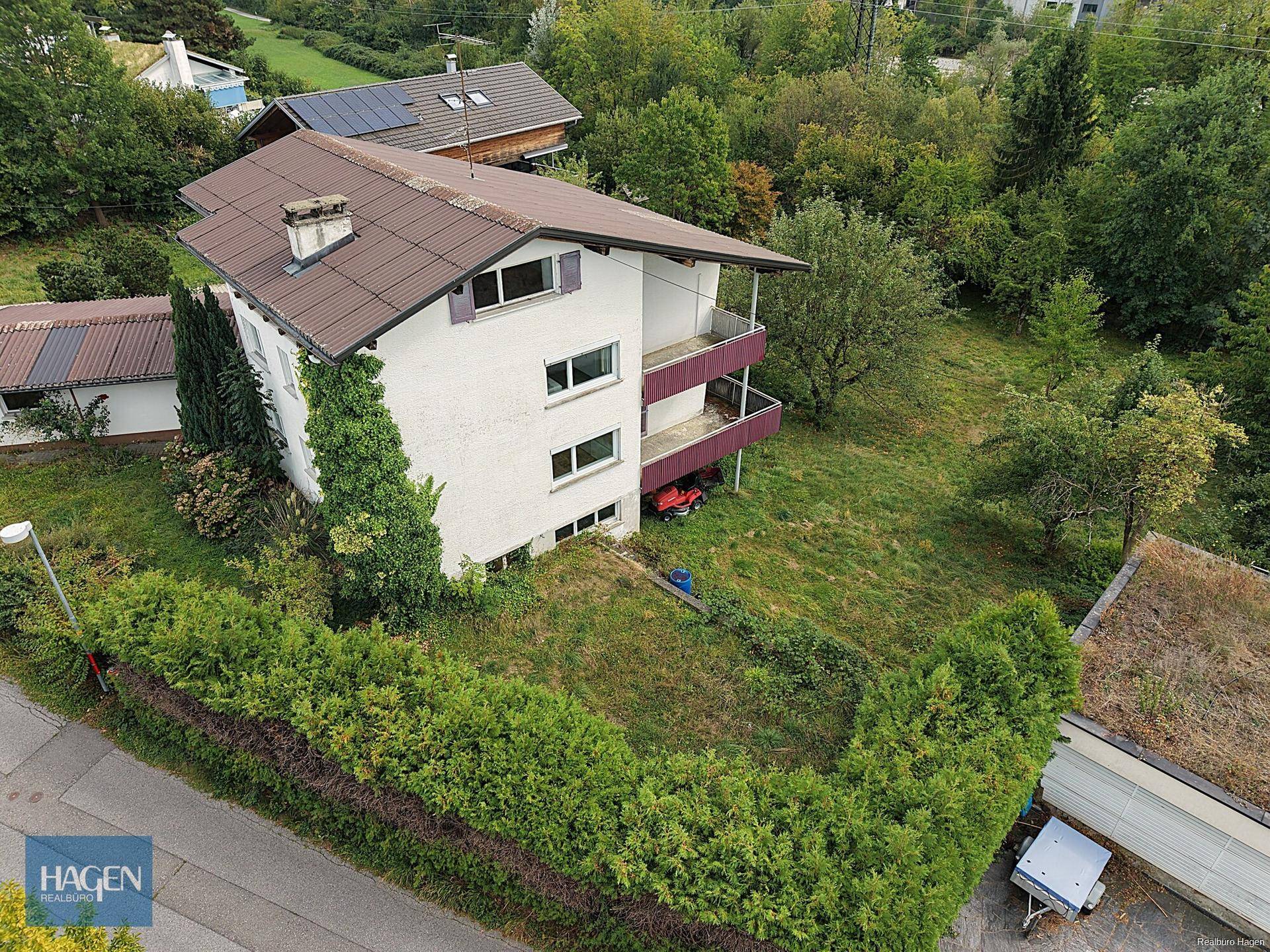 Luftaufnahme des Hauses mit Garten, Hecke und umliegender grüner Landschaft.