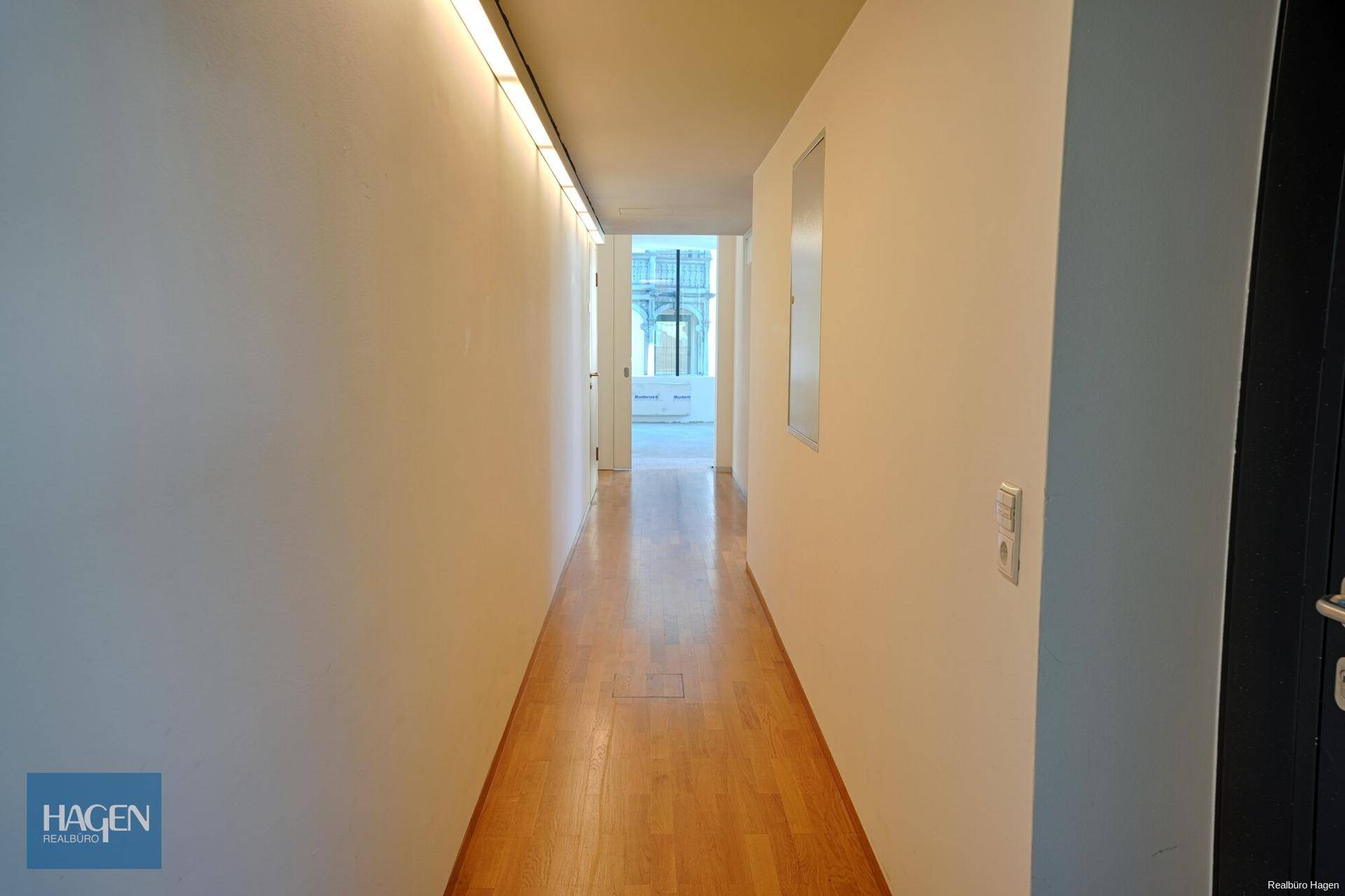 Heller Flur mit Holzfußboden und Blick auf einen weiteren Bereich des Gebäudes.