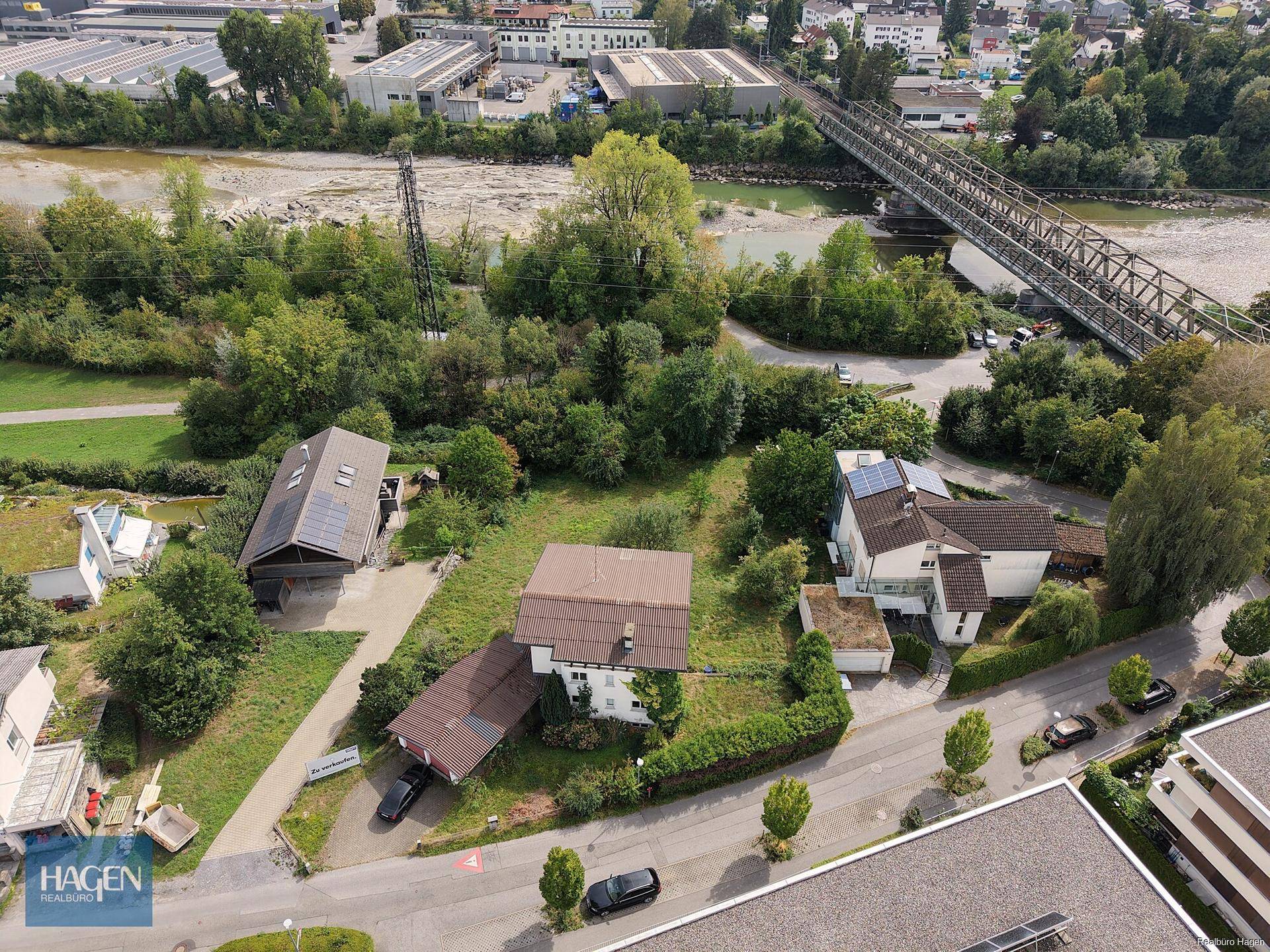 Weitläufige Luftaufnahme des Anwesens mit umliegender Bebauung, Flusslandschaft und Brücke.
