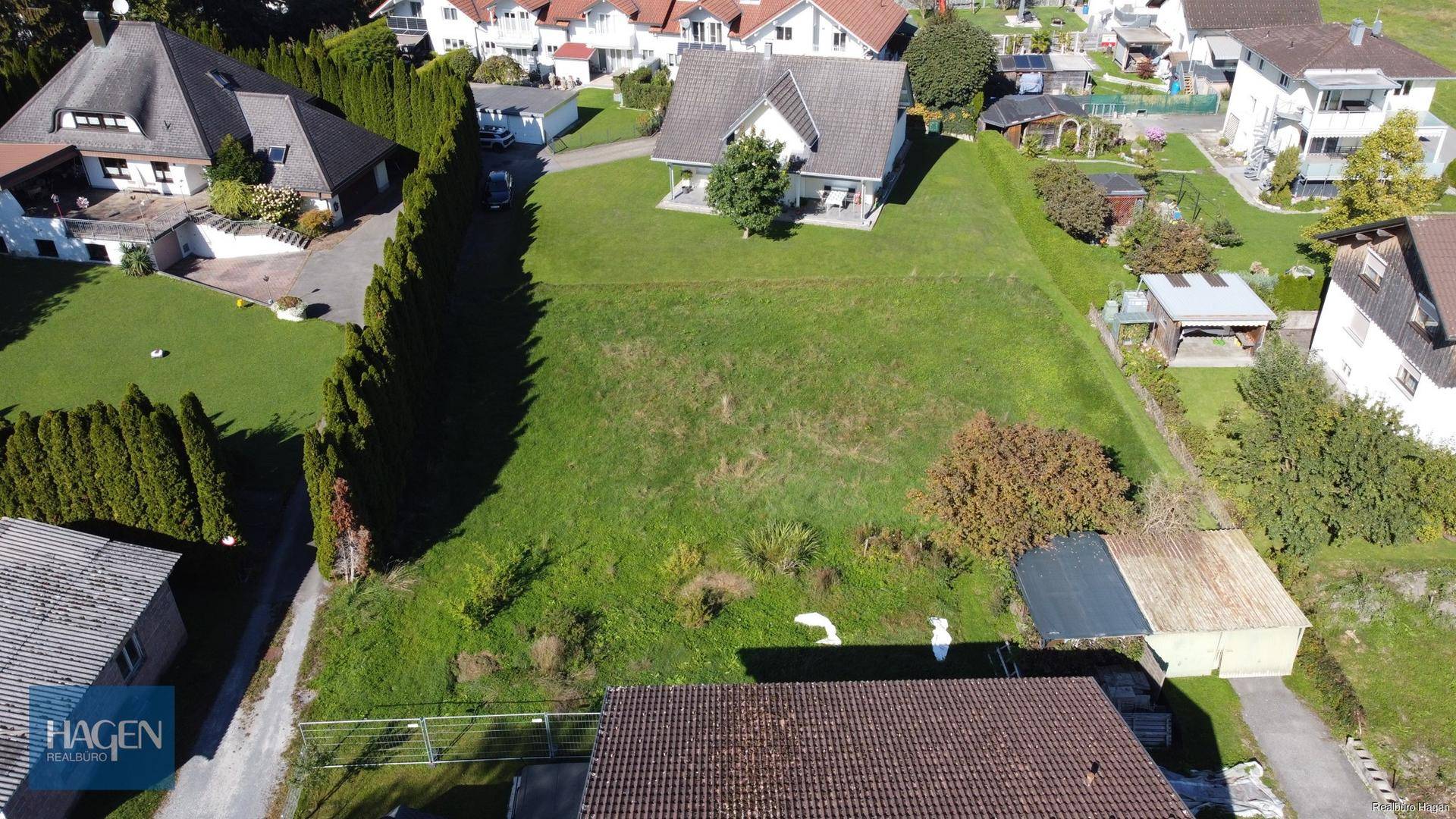 Luftaufnahme eines abfallenden Wiesengrundstücks mit umliegenden Wohnhäusern und Gärten.