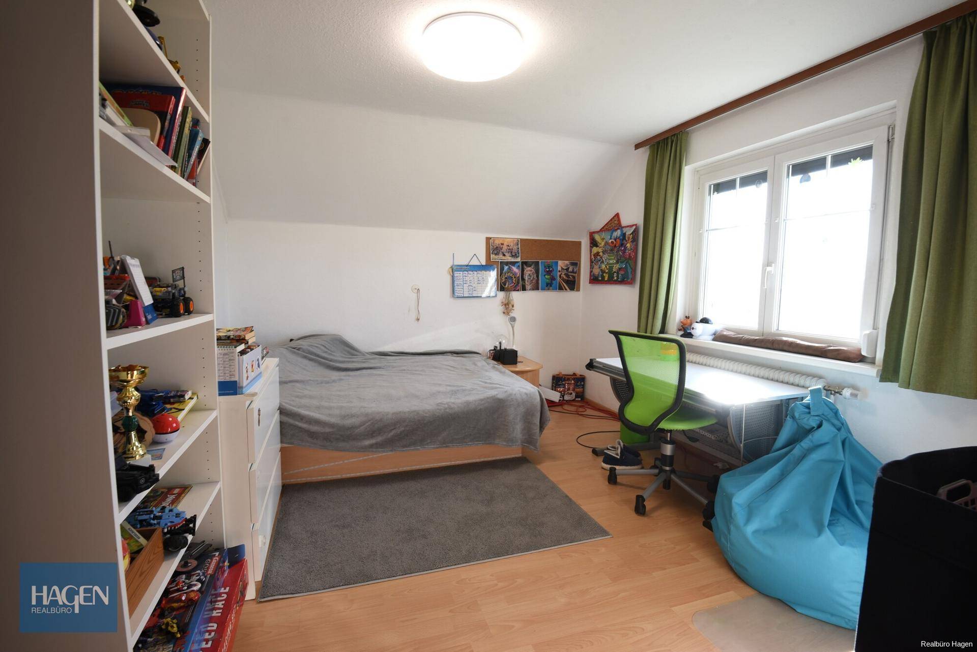 Kinderzimmer im Dachgeschoss mit Schrägen, Laminatboden und Schreibtisch.