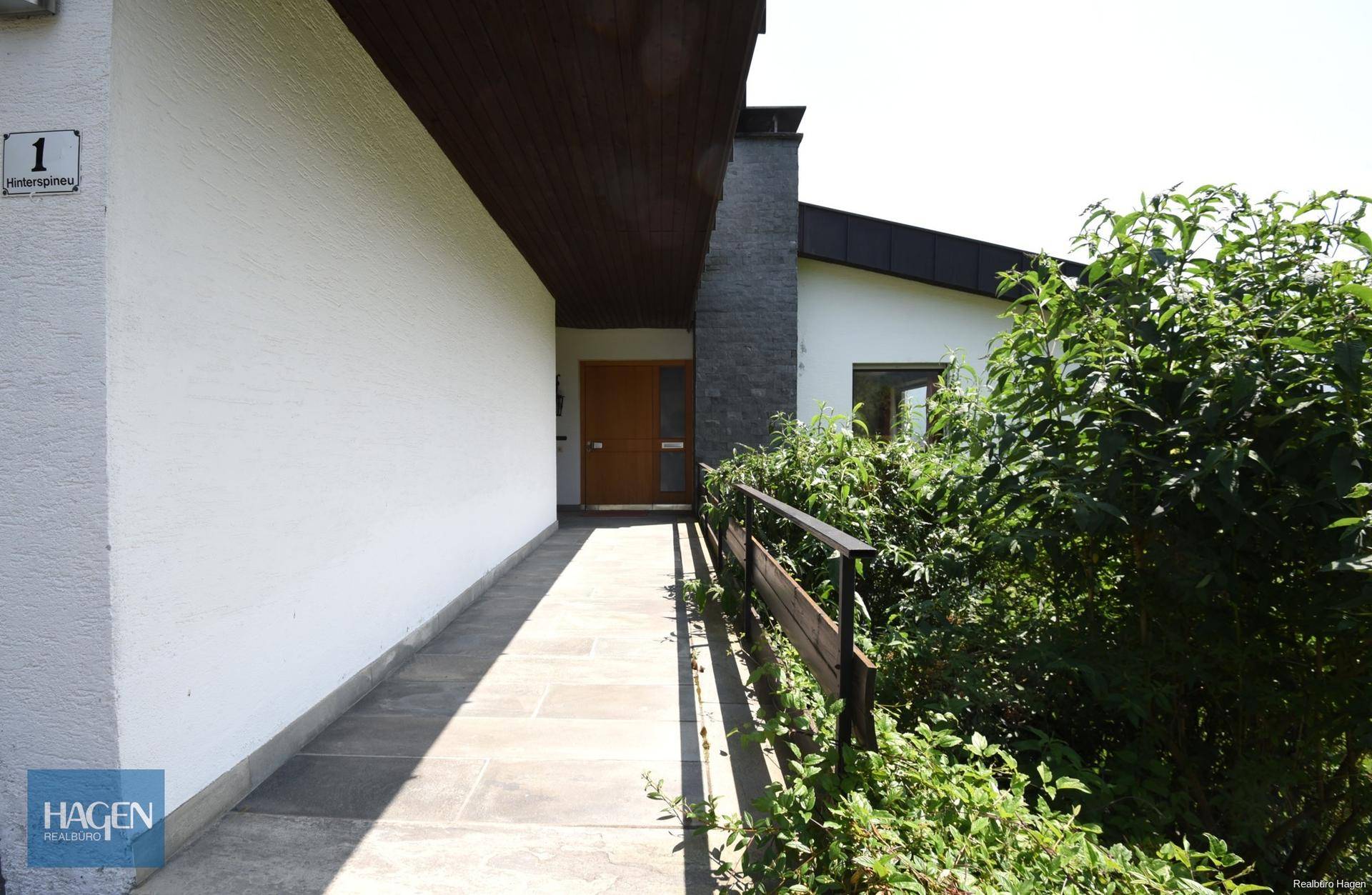 Eingangsbereich des Hauses mit Rampe und umgebender Bepflanzung.