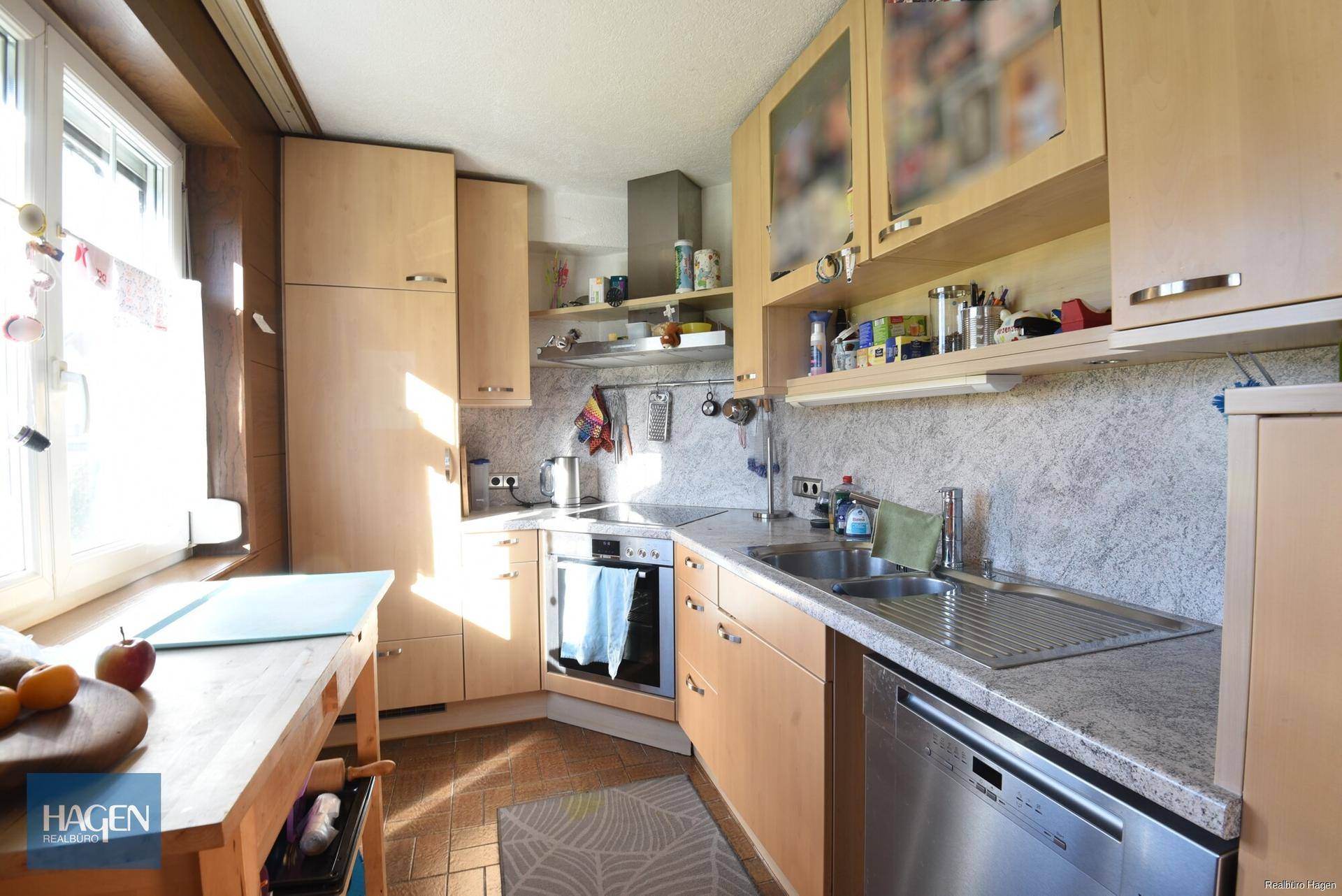 Funktionale Küche mit hellen Holzschränken, Granitarbeitsplatte und Fenster.