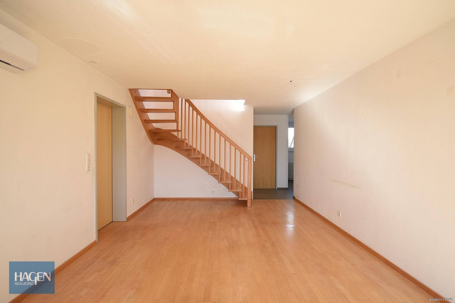 Geräumiger Flur mit Holztreppe und Parkettboden, der die verschiedenen Ebenen verbindet.