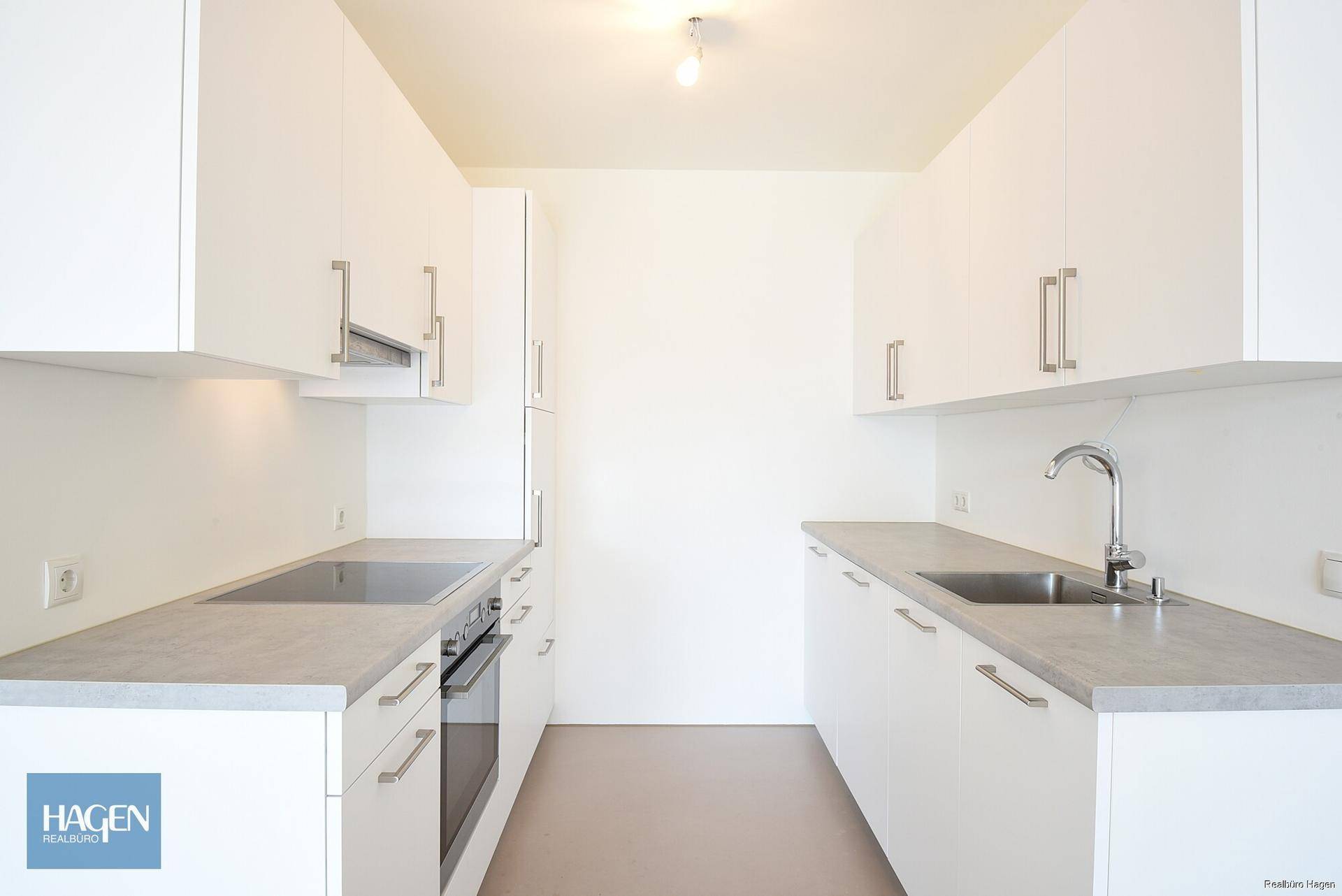 Moderne Einbauküche mit weißen Schränken, Induktionskochfeld und integriertem Backofen.