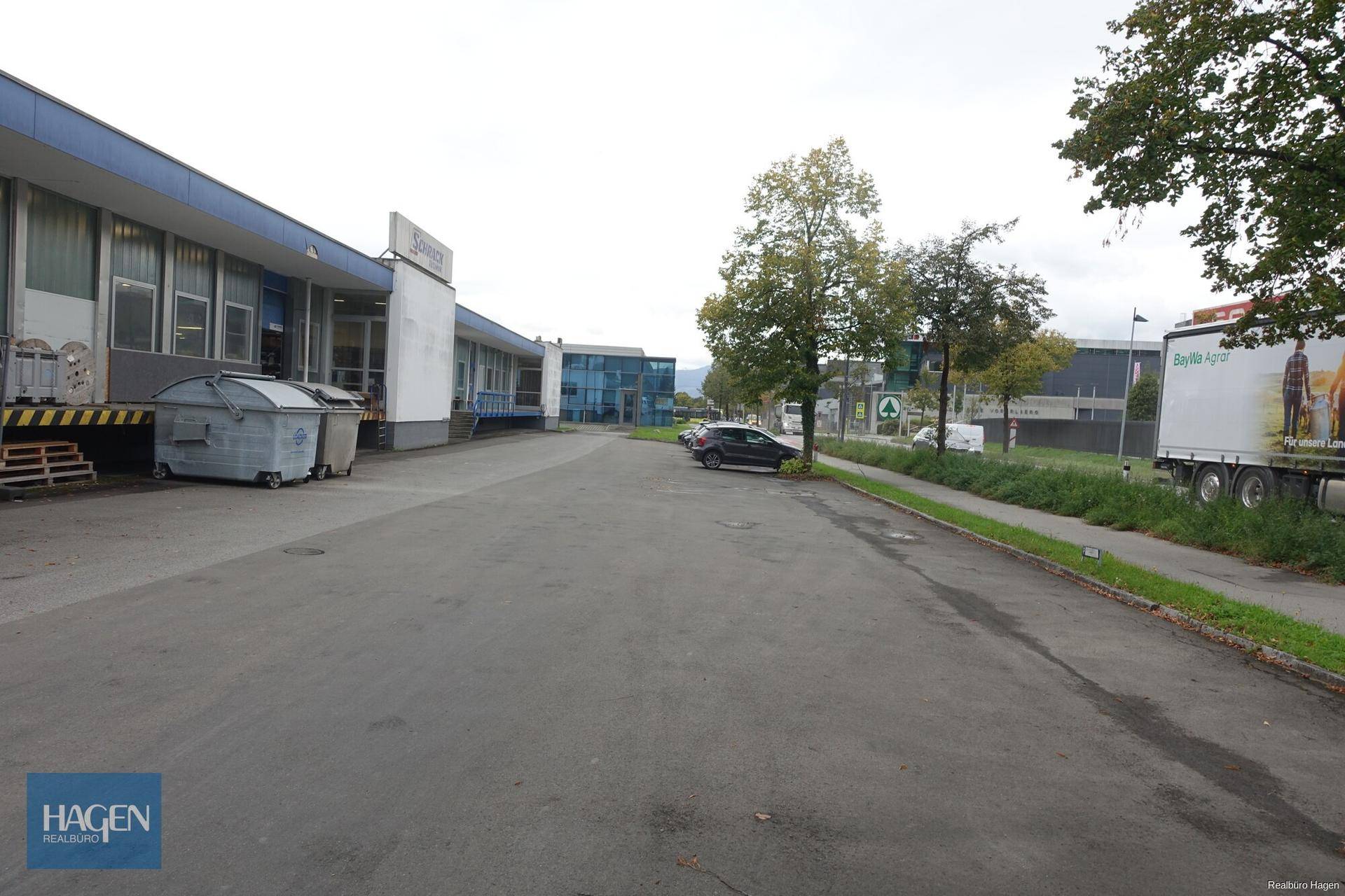Außenbereich des Gebäudes mit großem Parkplatz, Laderampe und Blick auf die Umgebung.