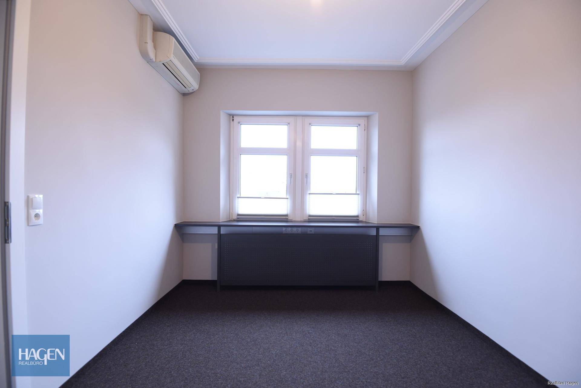 Leeres Büro mit Fenster, Klimaanlage und dunklem Boden, bereit zur Nutzung.