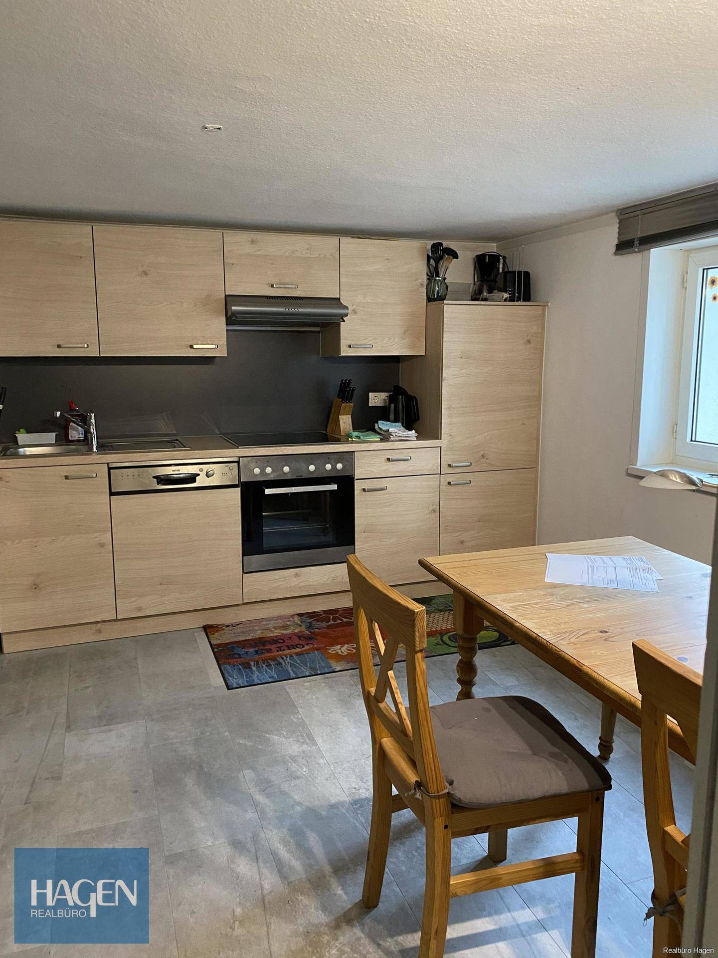 Moderne Einbauküche mit Holzelementen, Essbereich und einem Fenster für Tageslicht.