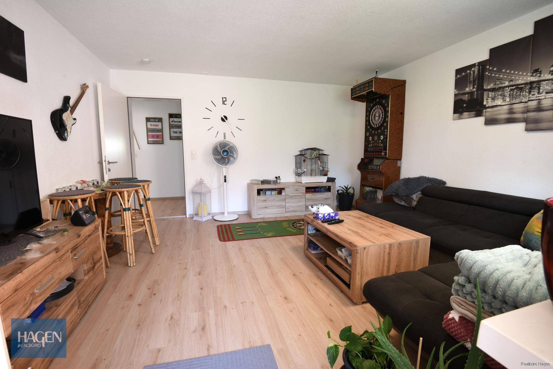 Geräumiges Wohnzimmer mit Laminatboden, Sofa und dekorativen Elementen, hell und einladend.