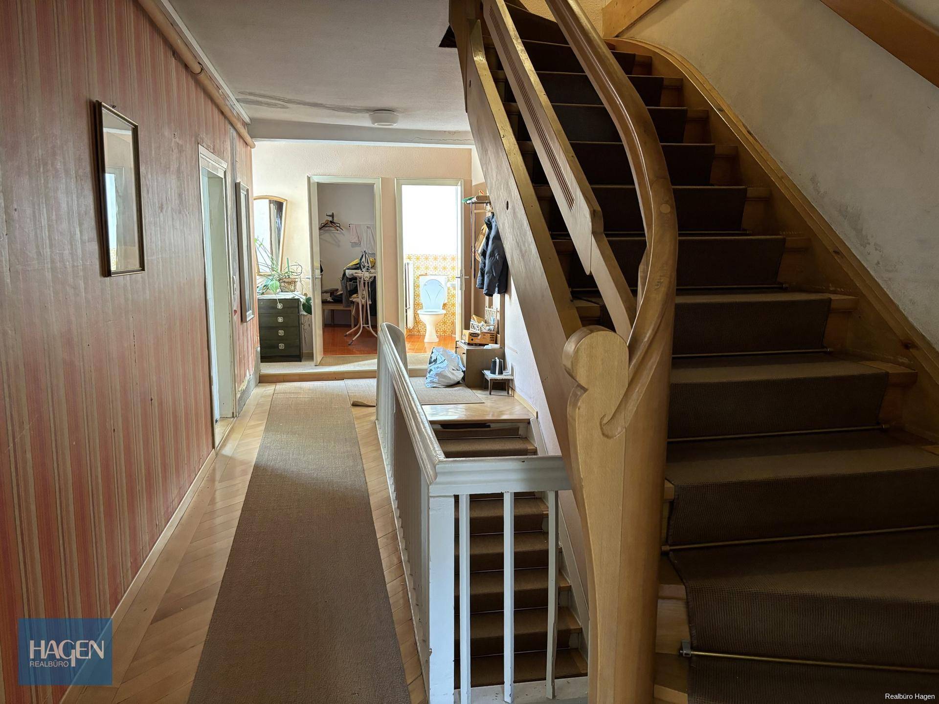 Geräumiger Flur mit Holztreppe und Zugang zu verschiedenen Räumen.