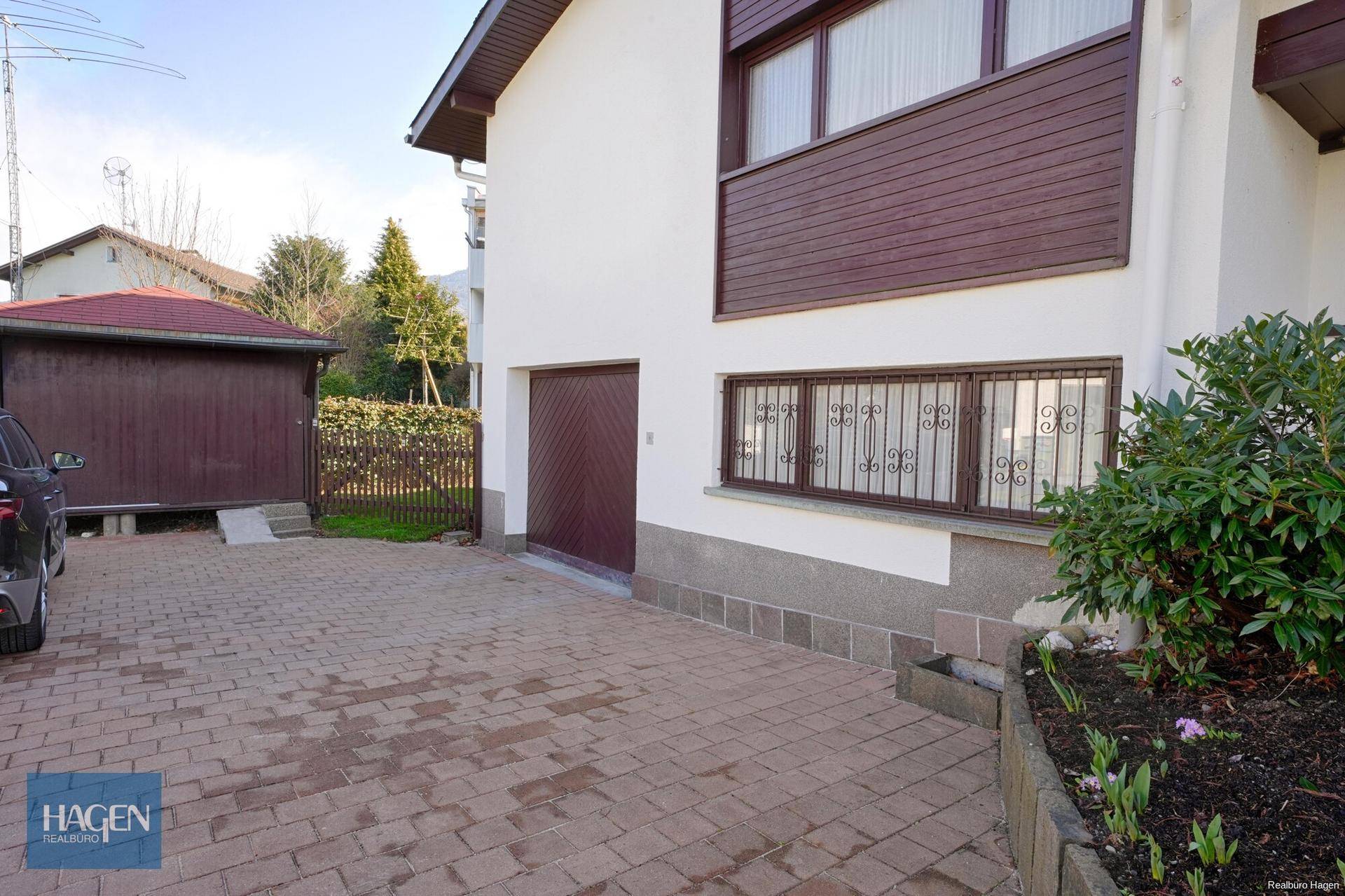 Einfahrt zum Haus mit Garage und einem kleinen Vorgartenbereich.