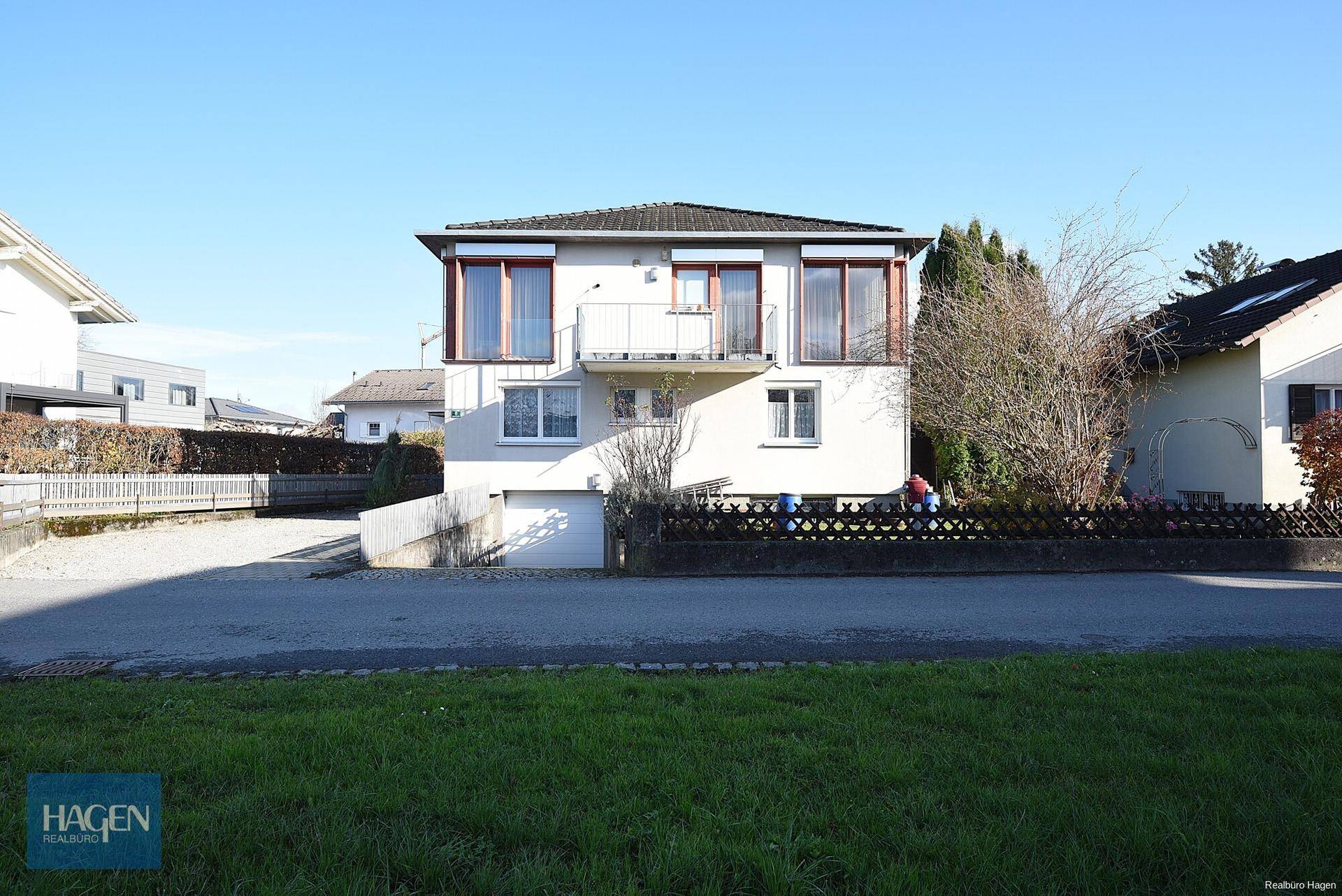 Ansicht des Hauses von der Straße mit Balkon und Zufahrt an einem sonnigen Tag.