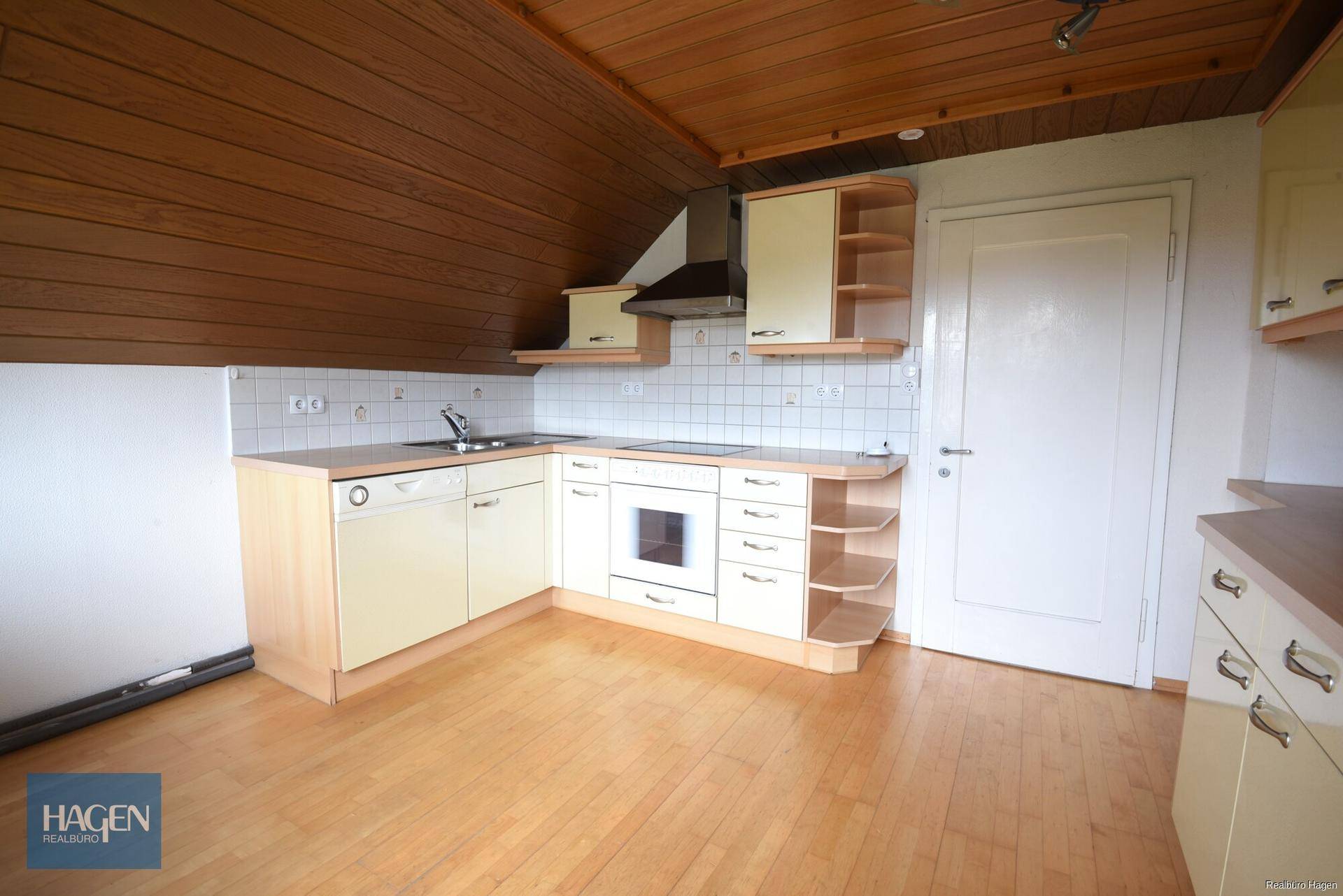 Funktionale Dachgeschossküche mit hellen Einbauschränken, Kochfeld und Backofen.