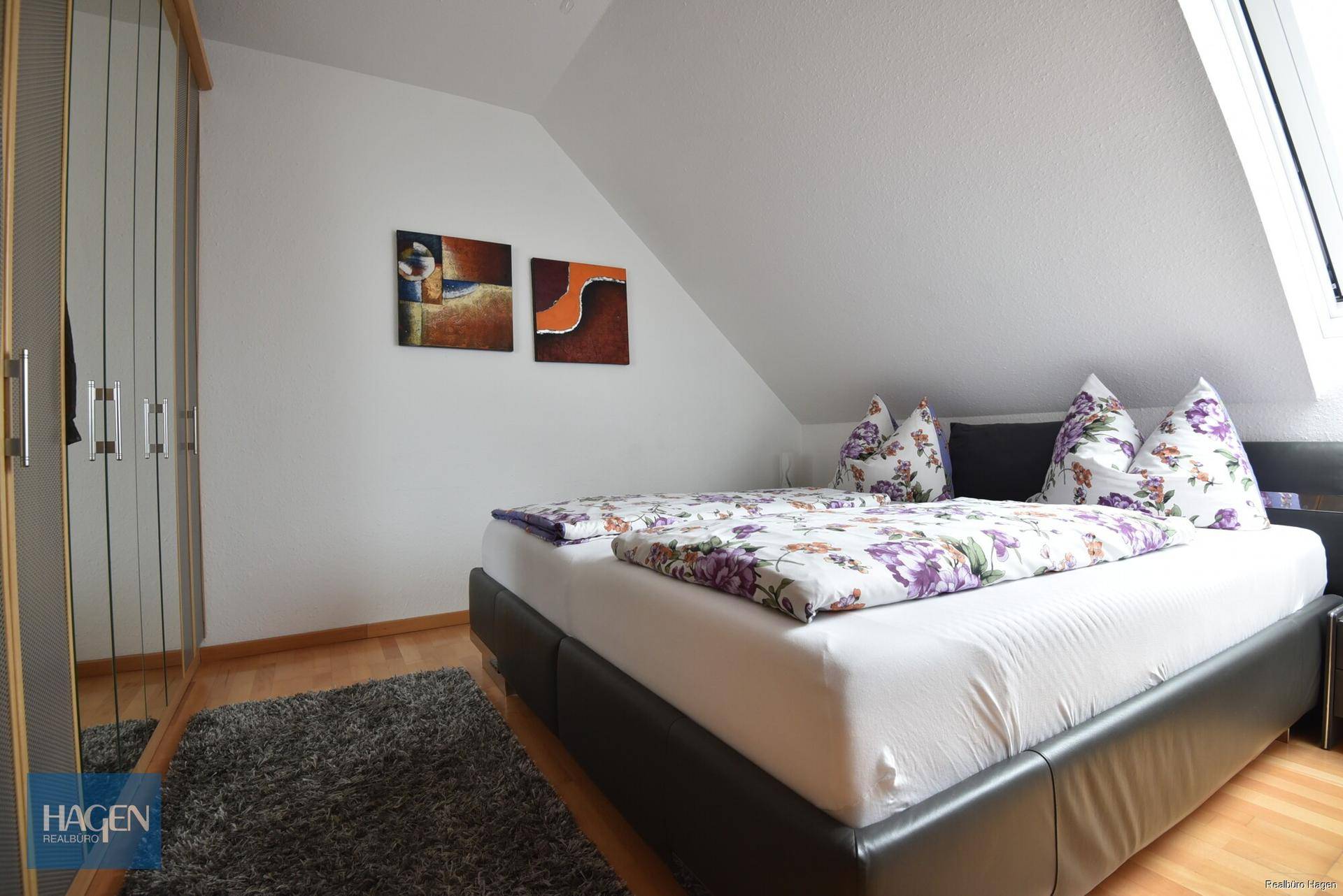 Schlafzimmer im Dachgeschoss mit Doppelbett, Kleiderschrank und Dachfenster.