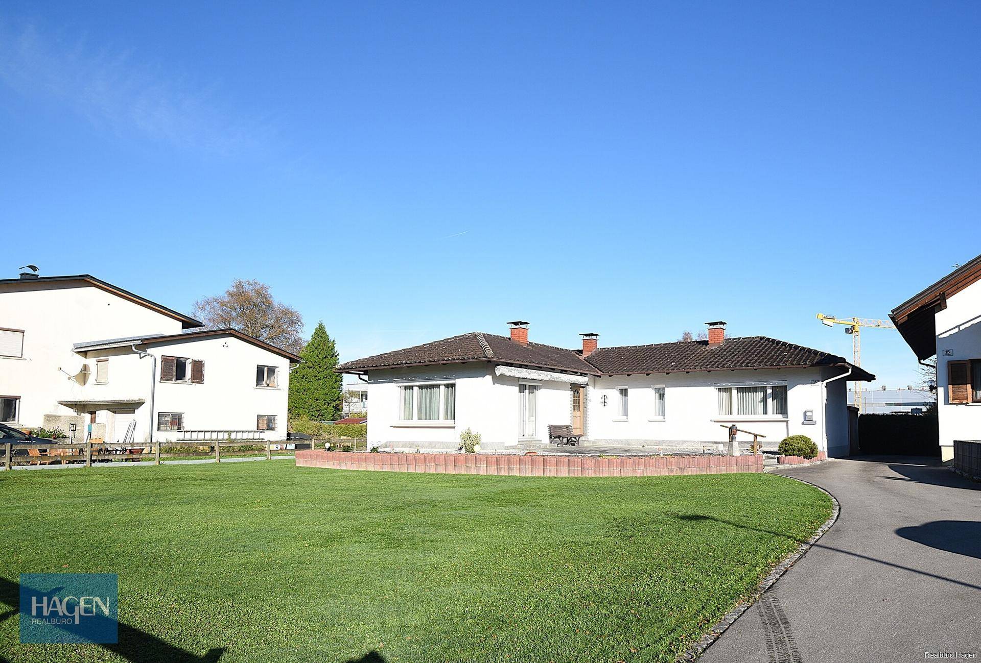 Einfamilienhaus mit gepflegtem Vorgarten und großer Rasenfläche unter blauem Himmel.