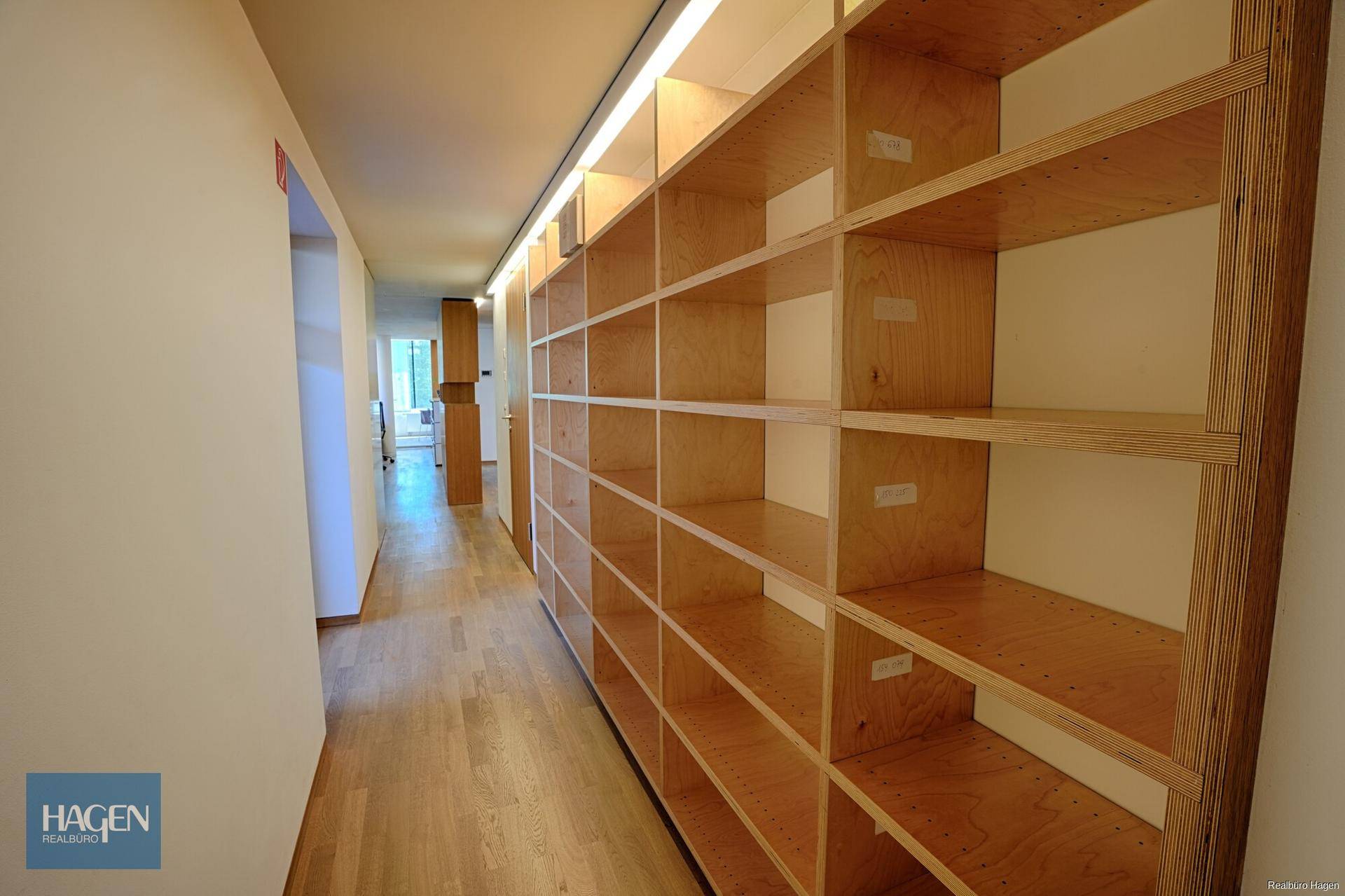 Langer Flur mit Holzregalen und indirekter Beleuchtung, ideal für Lagerung.