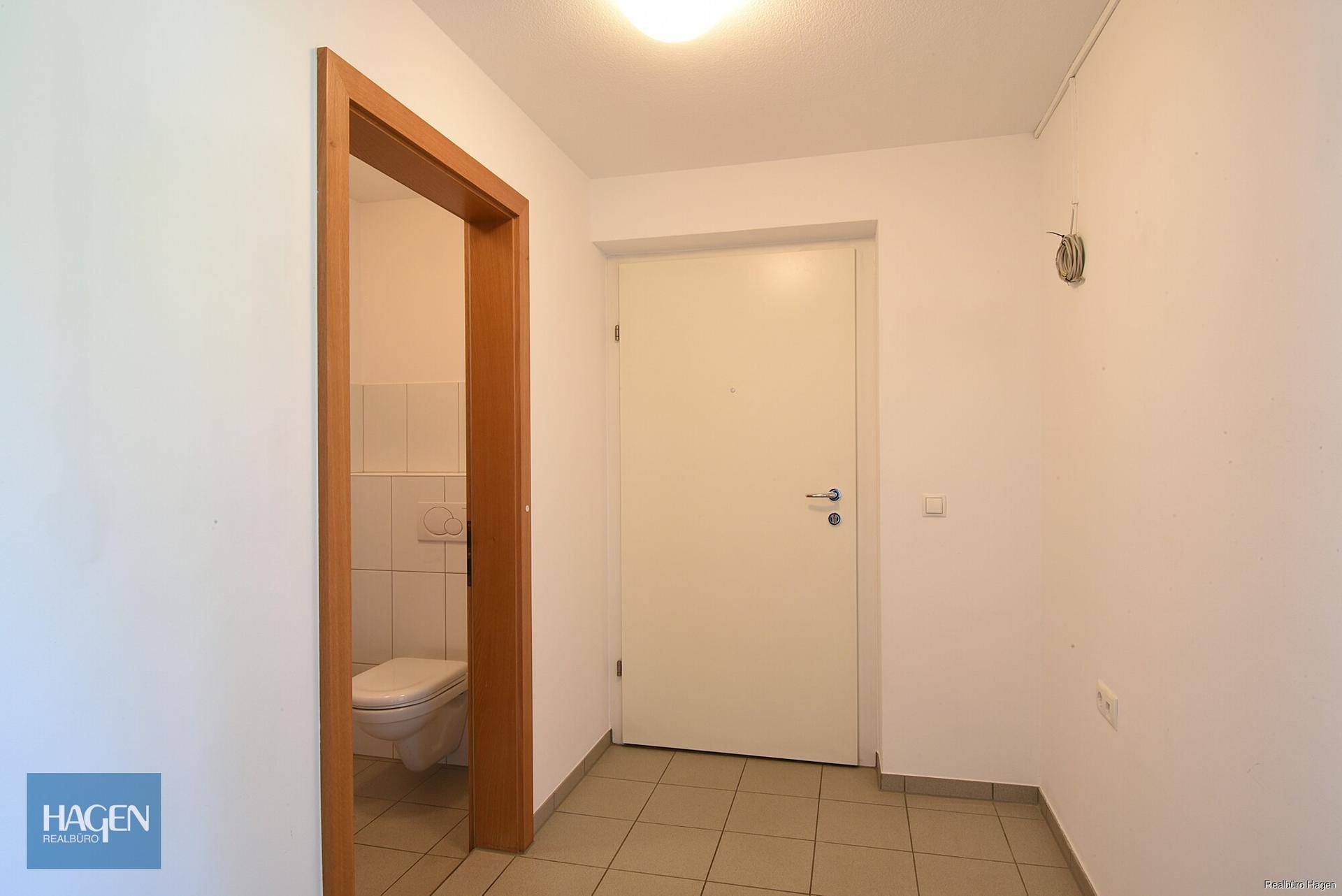 Eingangsbereich mit Fliesenboden und Zugang zu einem separaten Gäste-WC.