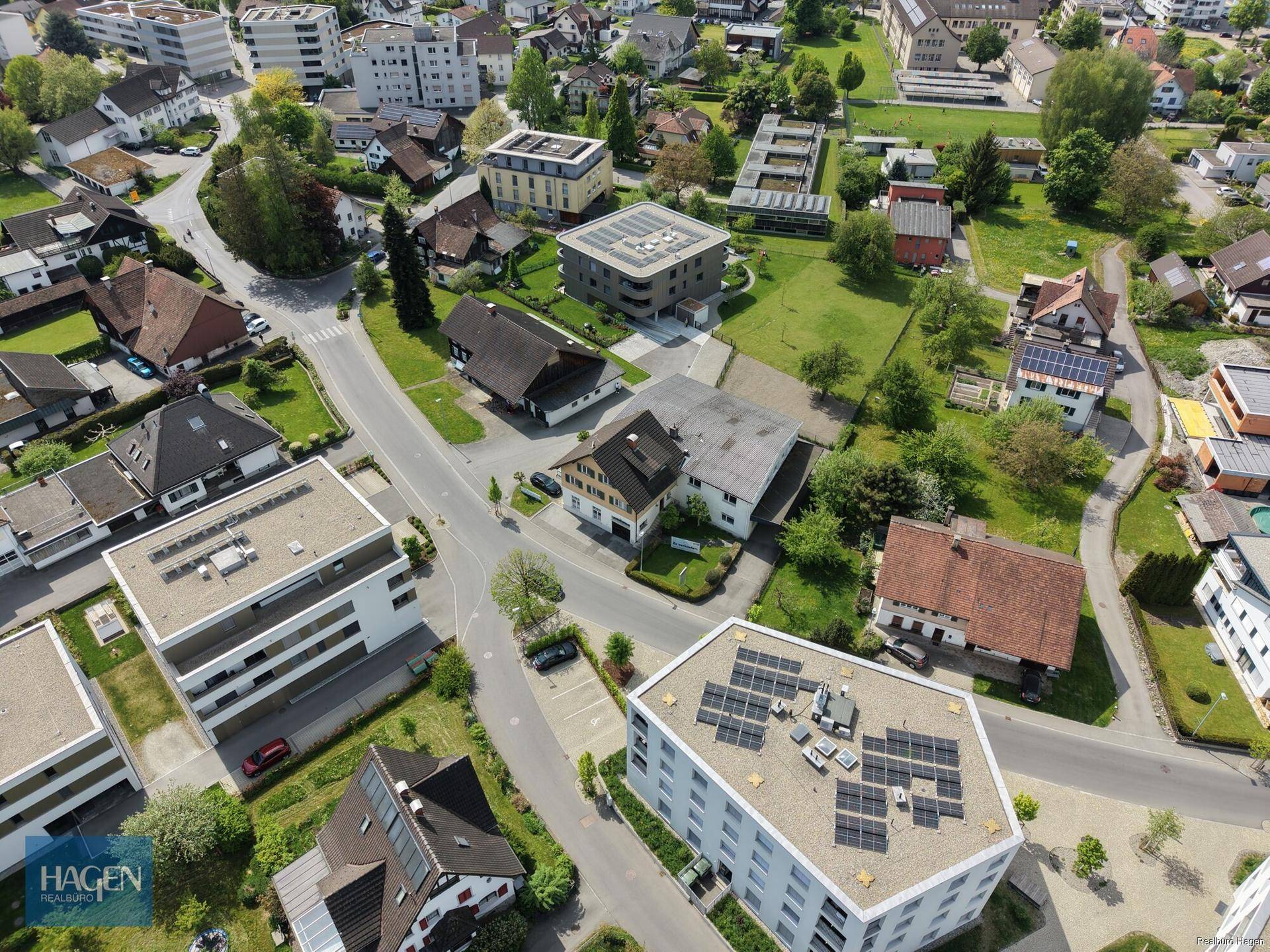 Weitläufige Luftaufnahme einer Wohnsiedlung mit verschiedenen Gebäuden, Straßen und viel Grünfläche.