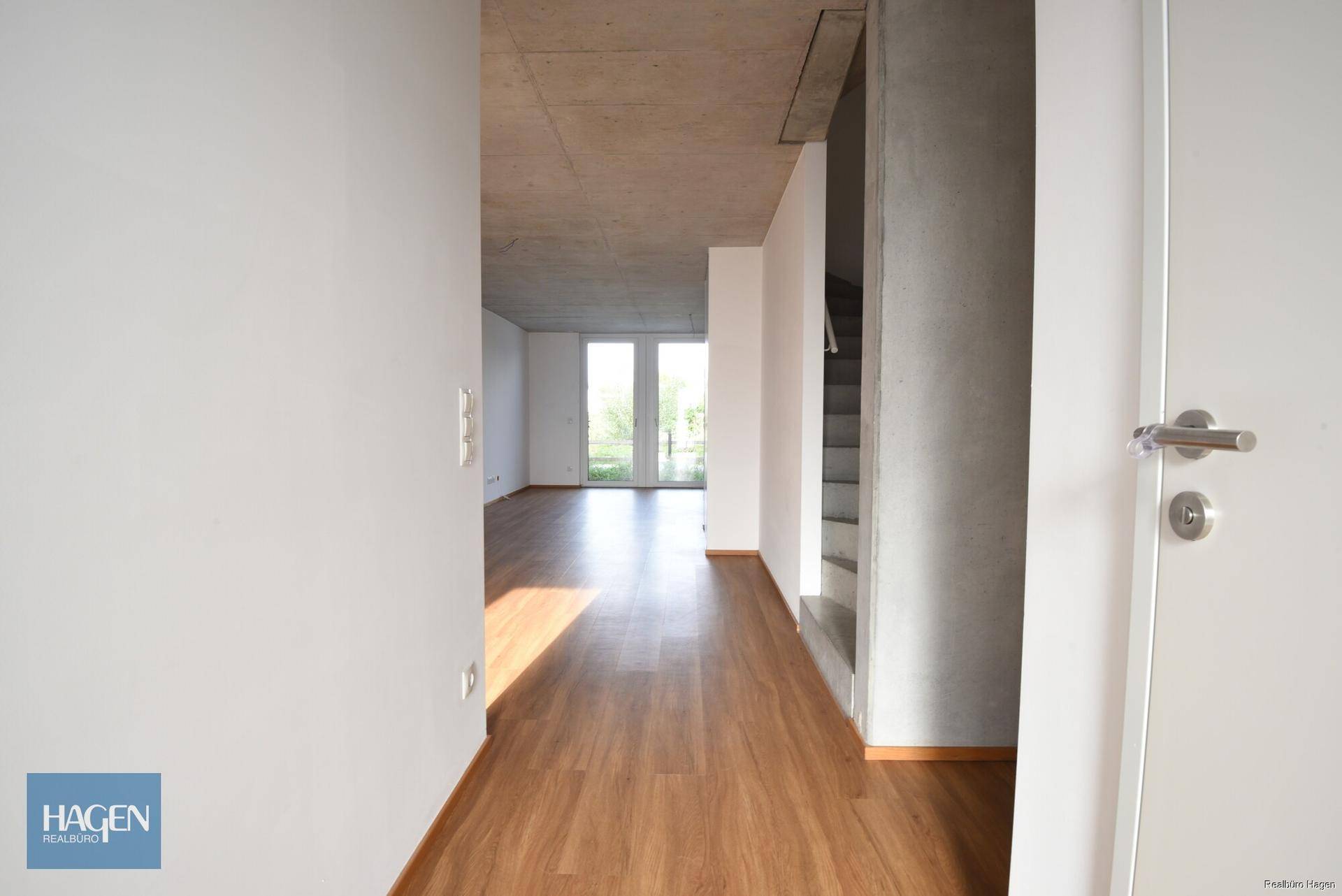 Heller Flur mit Laminatboden, weißen Wänden und Blick auf den Außenbereich.