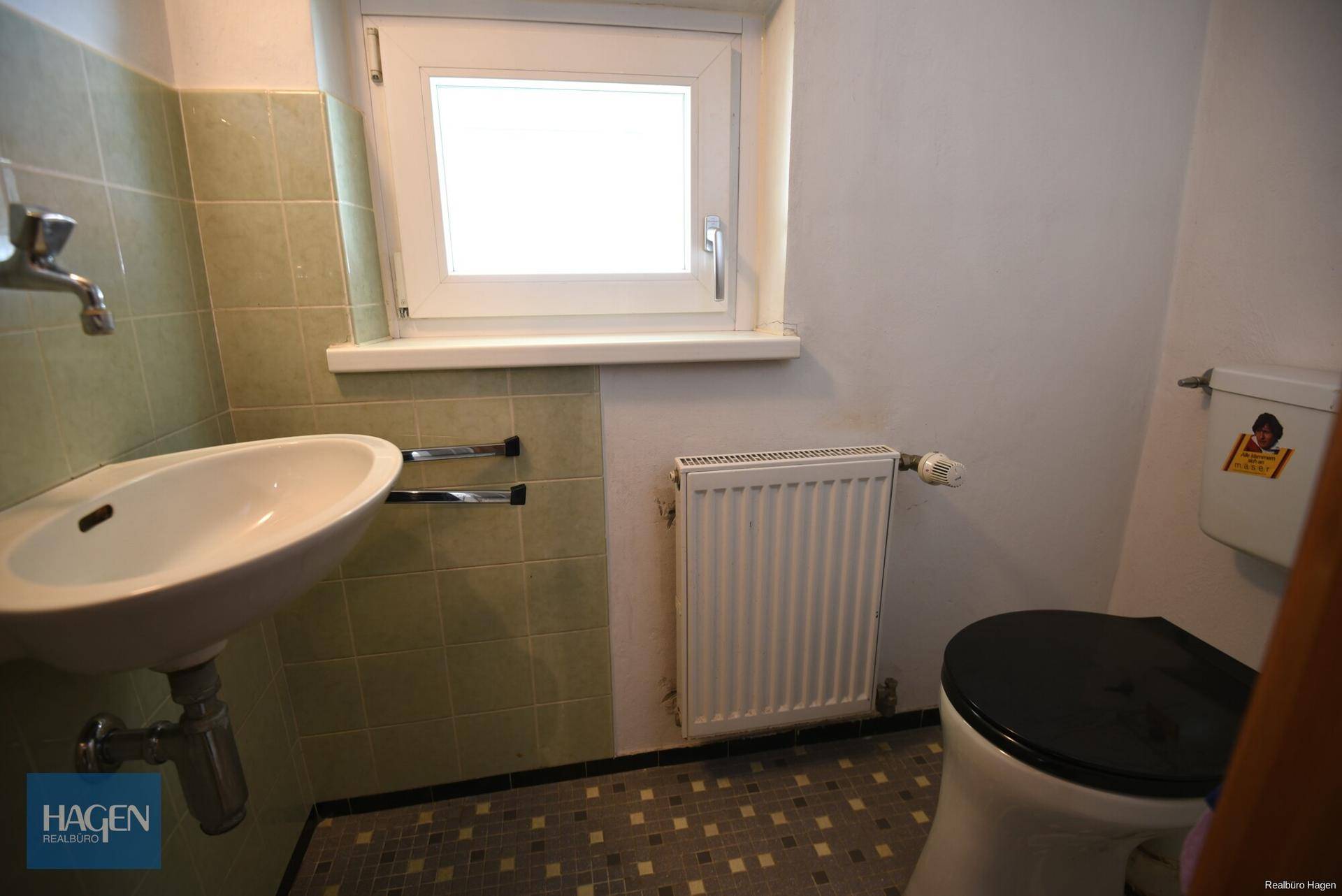Gäste-WC mit kleinem Waschbecken, Toilette und Fenster.