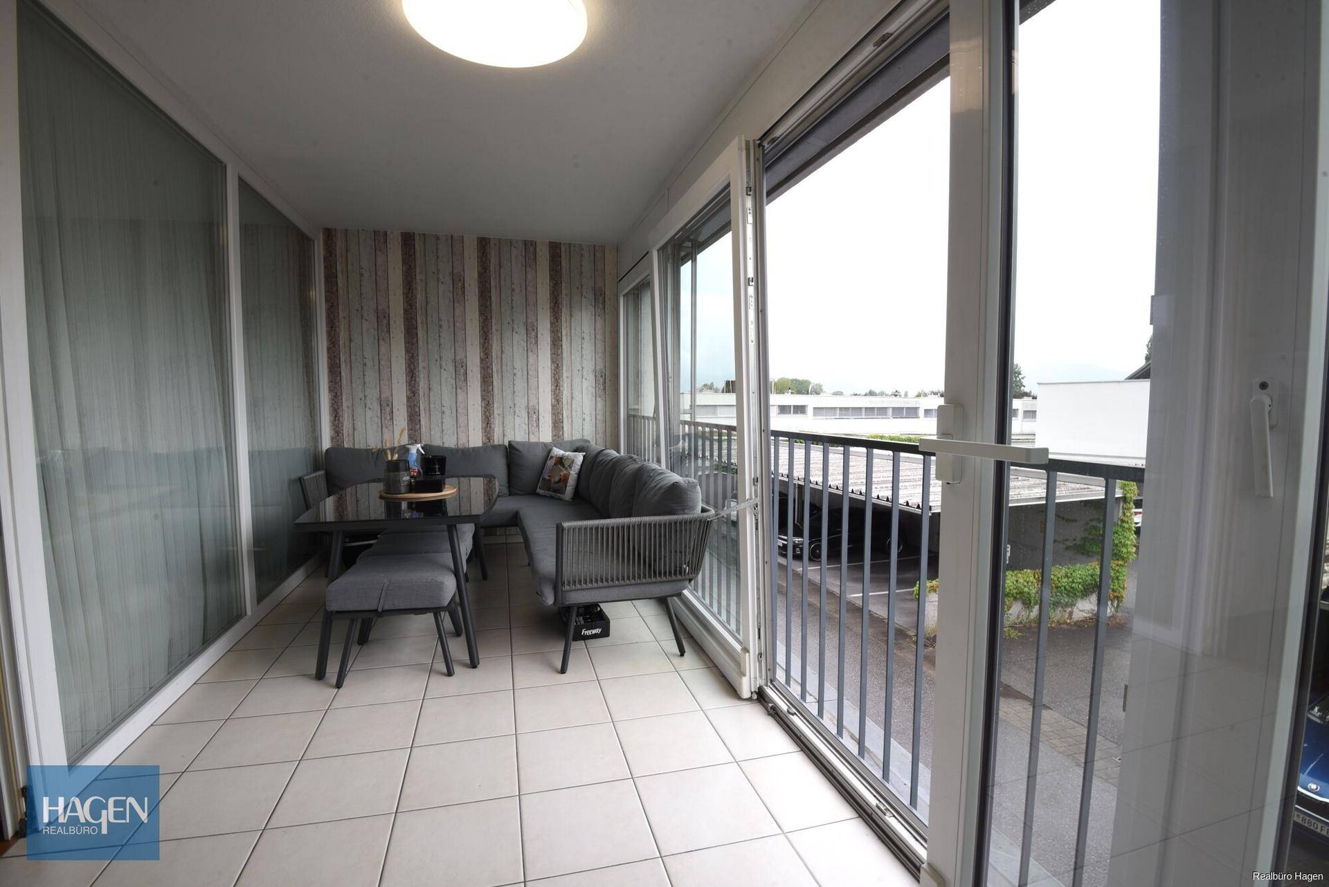Verglaster Balkon mit Sitzgelegenheiten und Blick auf die Umgebung.