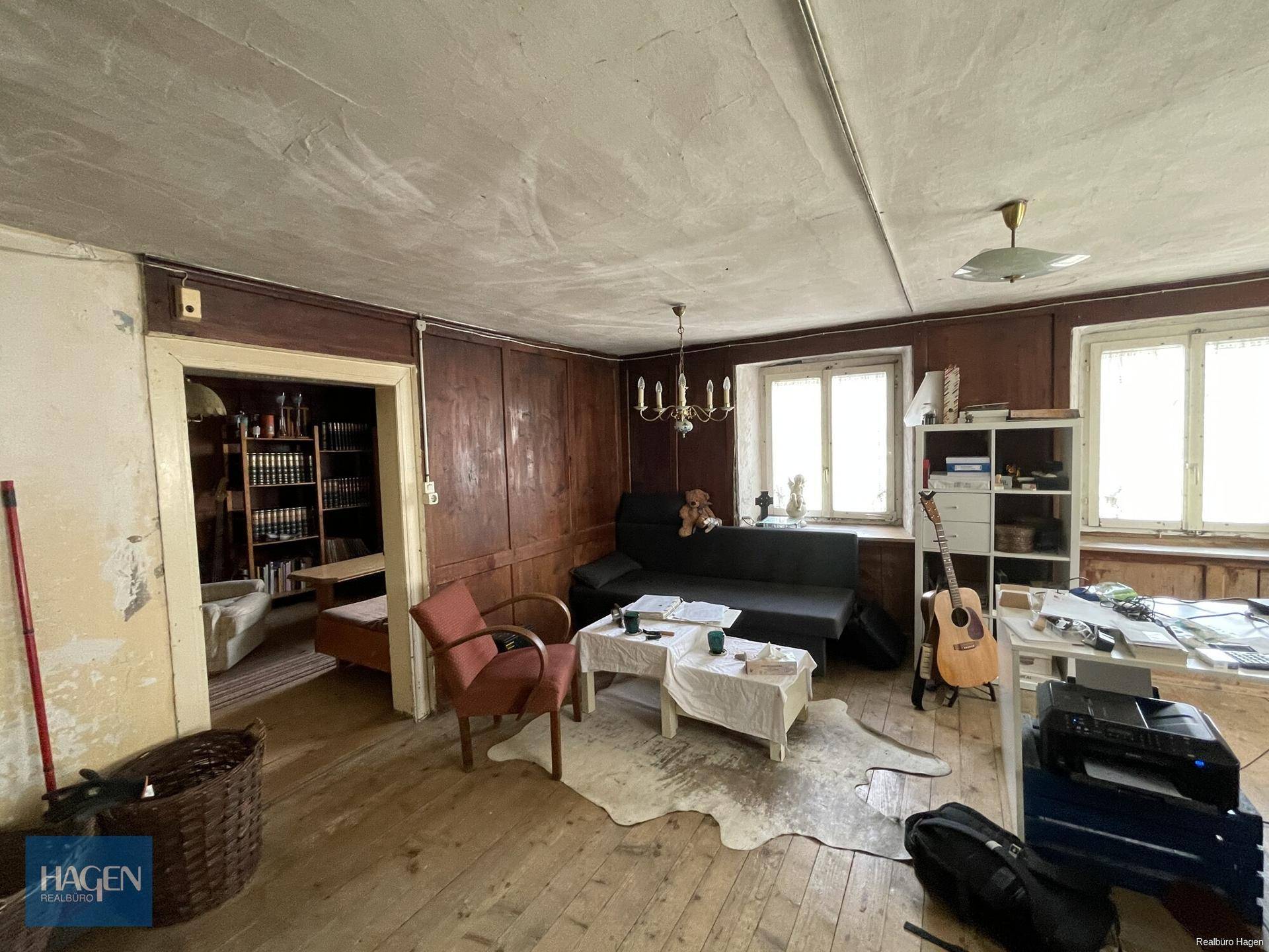 Traditionelles Wohnzimmer mit dunkler Holzvertäfelung, gemütlicher Sitzecke und Holzboden.