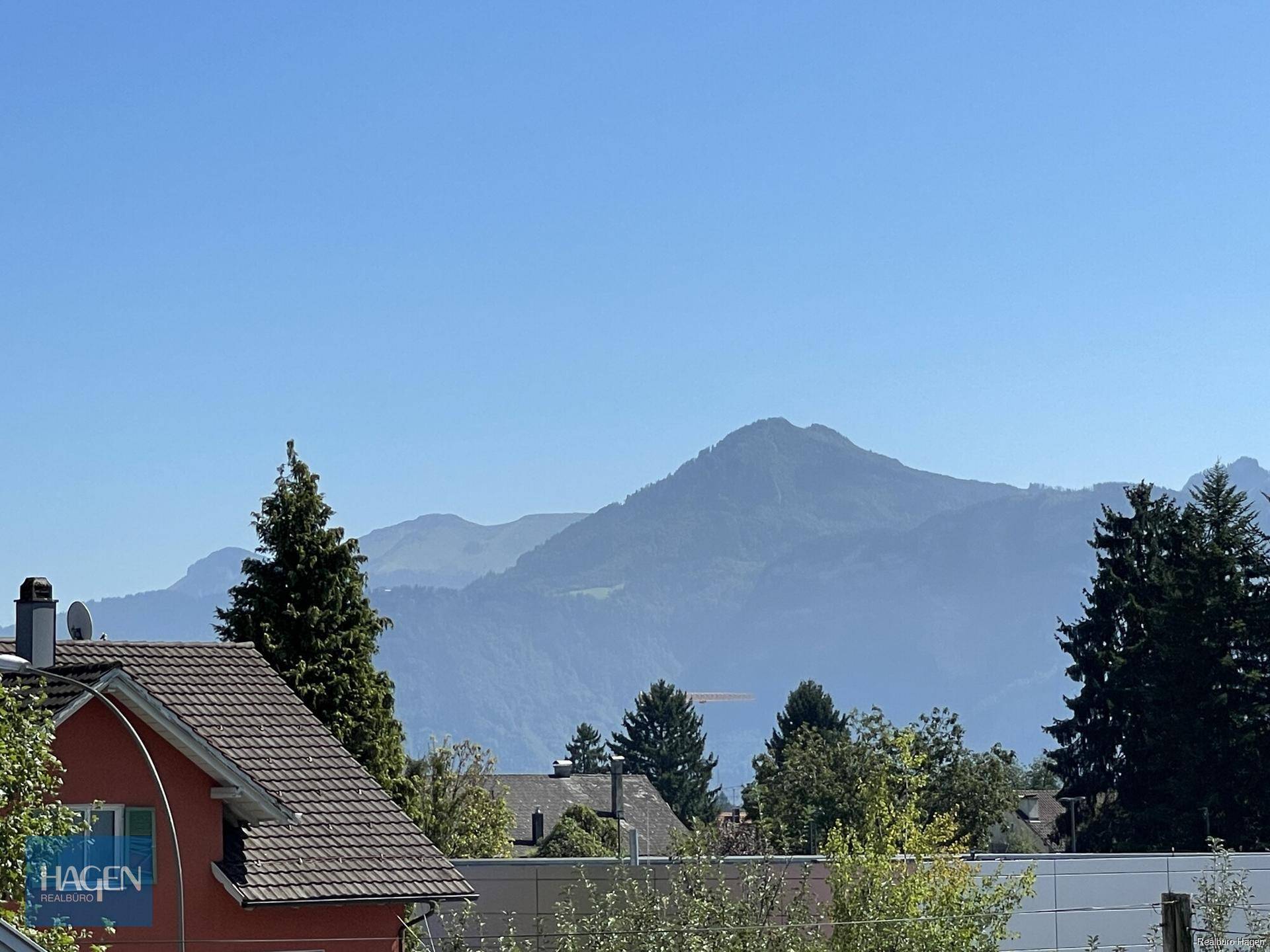 Panoramablick auf die majestätischen Berge und die grüne Landschaft unter klarem Himmel.