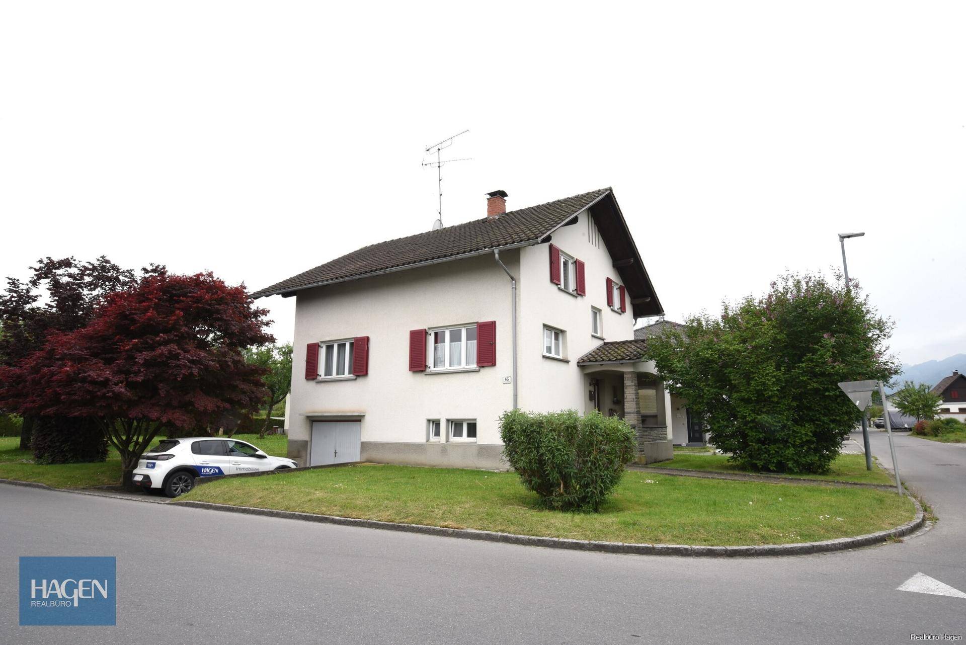 Einfamilienhaus mit Garage im Untergeschoss und gepflegtem Vorgarten.