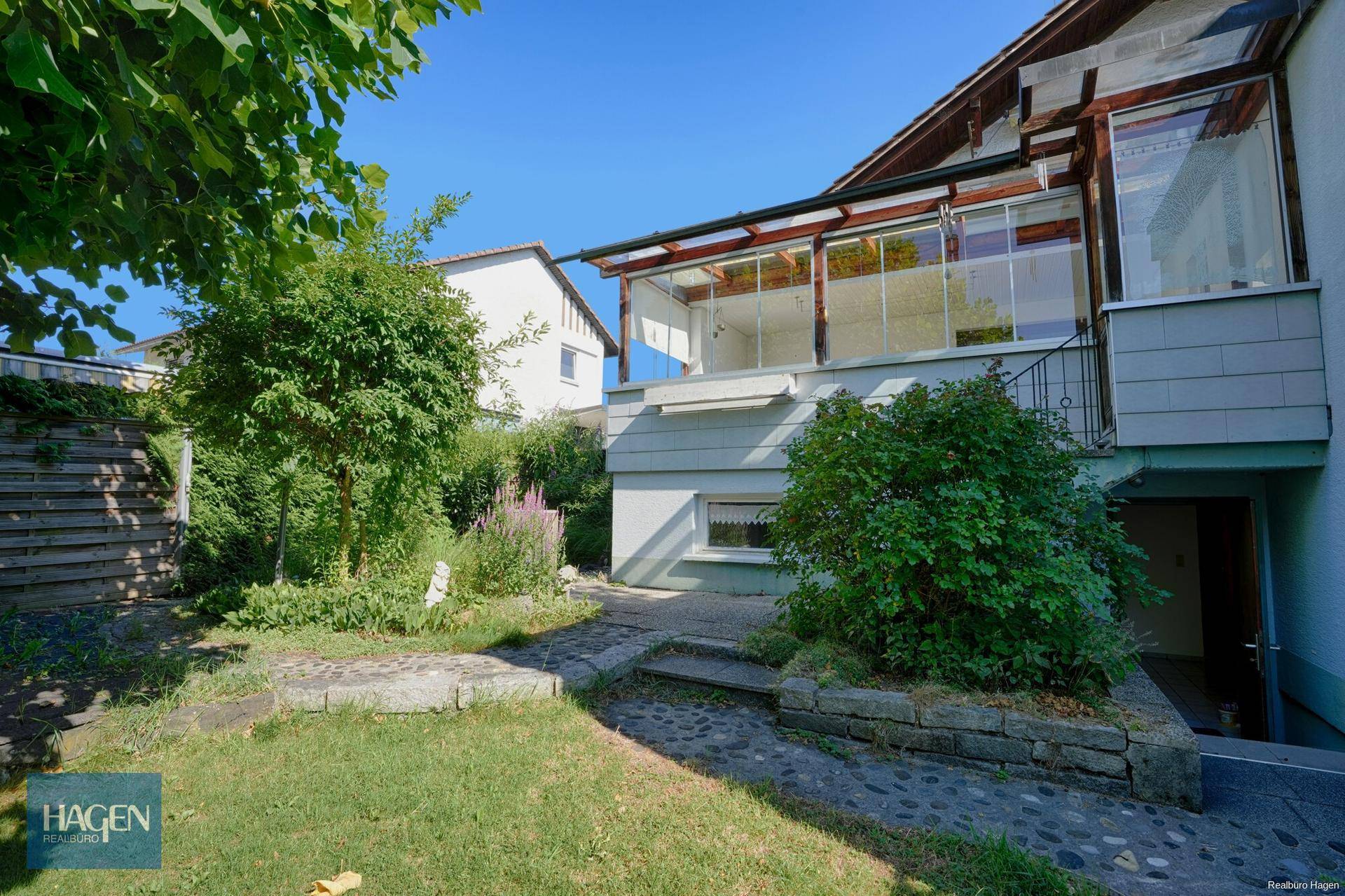 Gepflegter Gartenbereich mit Rasen, Sträuchern und Zugang zur Terrasse.