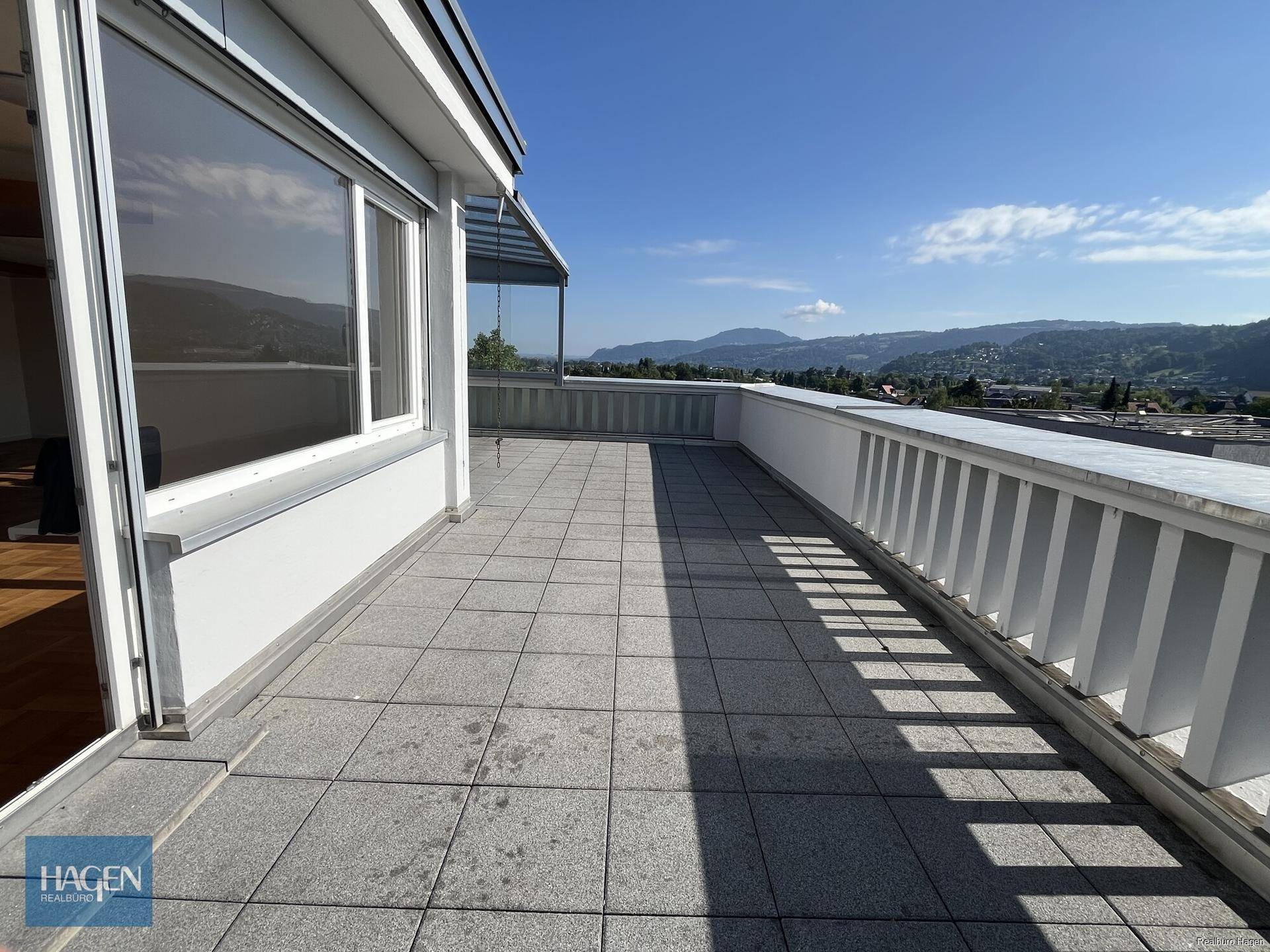 Lange Terrasse mit Fliesenboden und Geländer, bietet einen weiten Blick über die Umgebung.