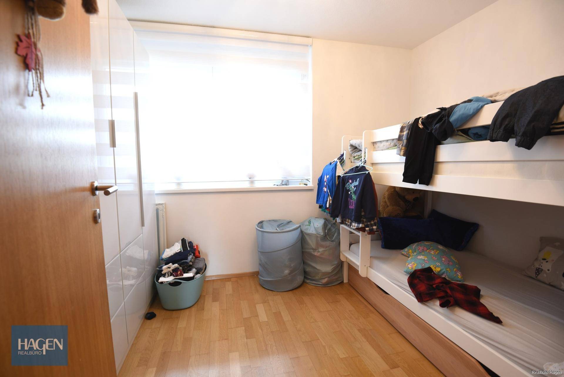 Kinderzimmer mit Etagenbett, hellem Fenster und ausreichend Platz für Spiel und Stauraum.