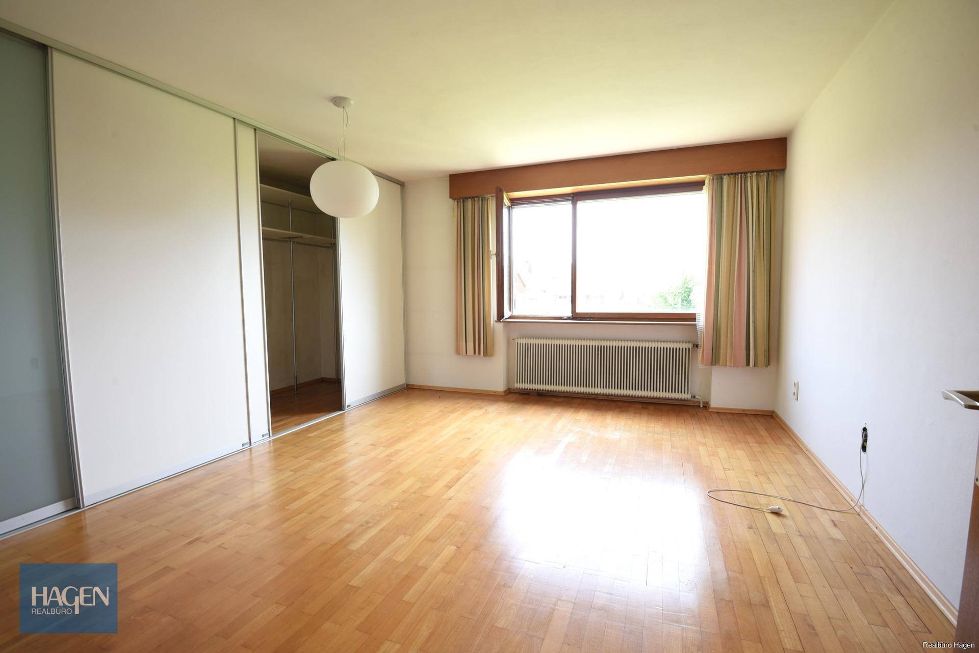 Helles Schlafzimmer mit Holzboden und großem Einbauschrank.