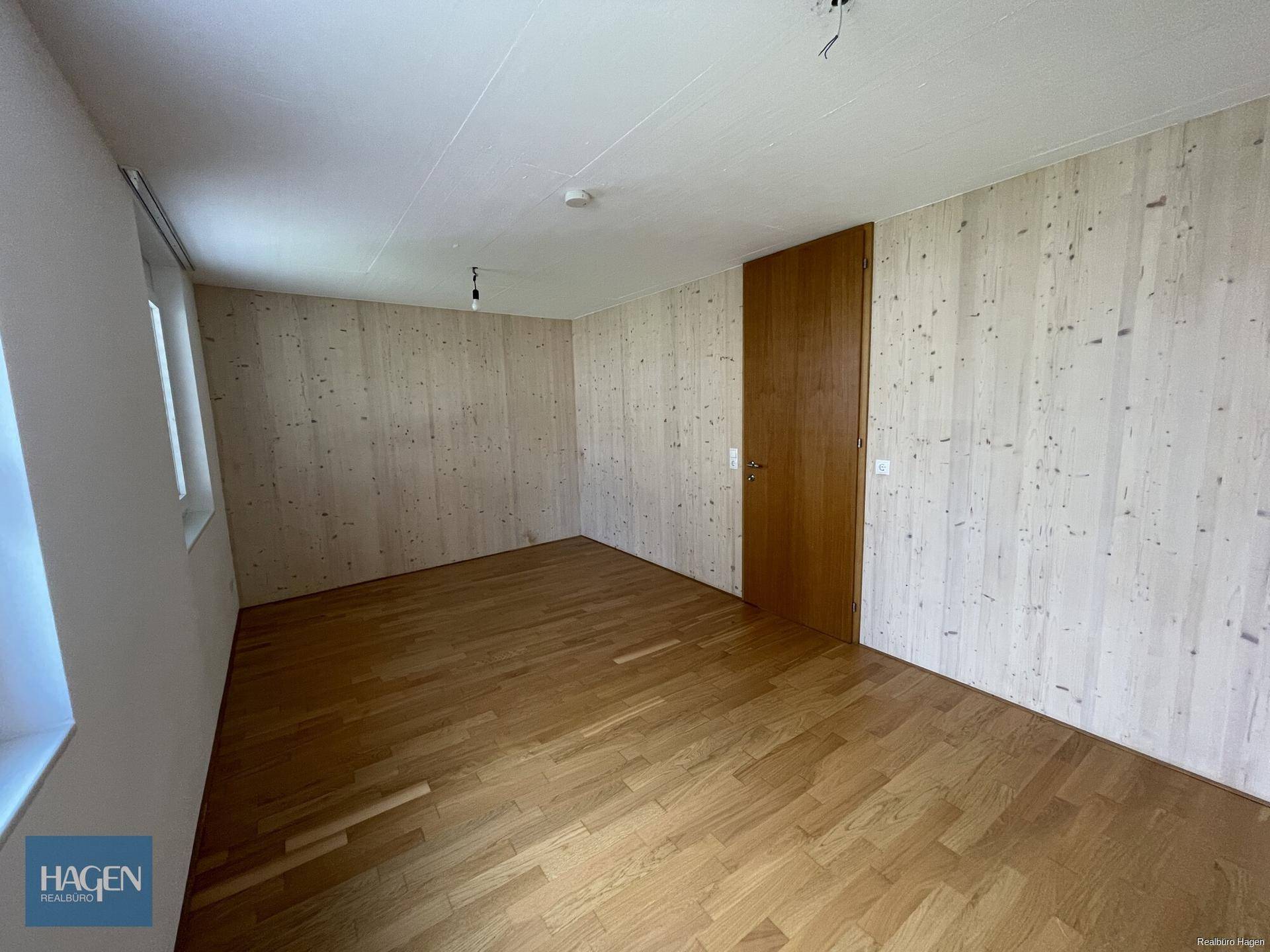 Helles Schlafzimmer mit Holzboden und Holzwänden, bereit zur individuellen Gestaltung.